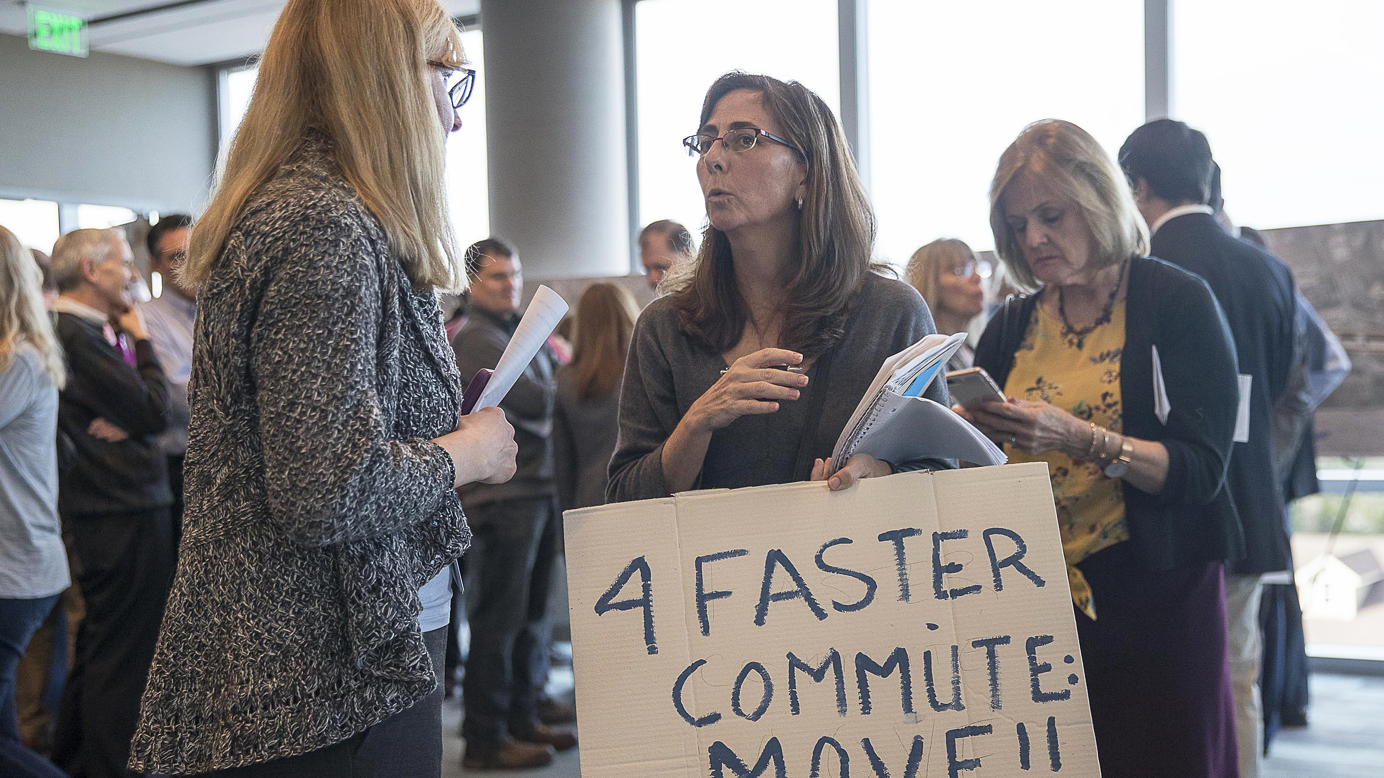 Sandy Springs resident Malia Jeffers holds a sign of protest while speaking with a GDOT project consultant during a GDOT open house meeting with North Fulton residents at the Sandy Springs City Hall in Sandy Springs, Tuesday, March 12, 2019. (ALYSSA POINTER/ALYSSA.POINTER@AJC.COM)