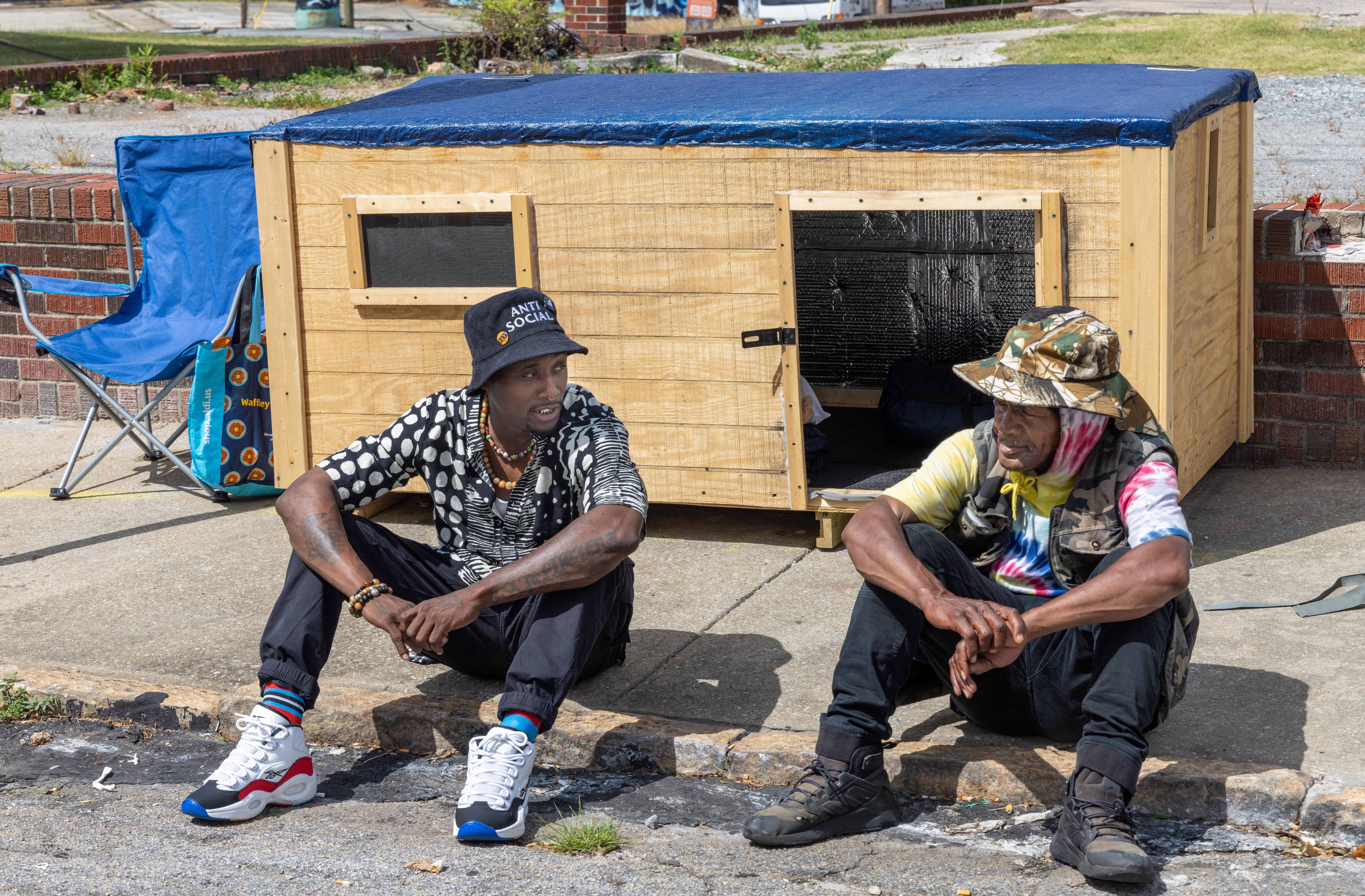 Brandon Brando (left) talks with Reginald Driskell, a homeless man living in southwest Atlanta who he befriended and constructed a 7 by 3 foot wooden structure for the man with circulating air to get him out of an old cardboard box he's been living in. He'd like to do that for others as well.
PHIL SKINNER FOR THE ATLANTA JOURNAL-CONSTITUTION.