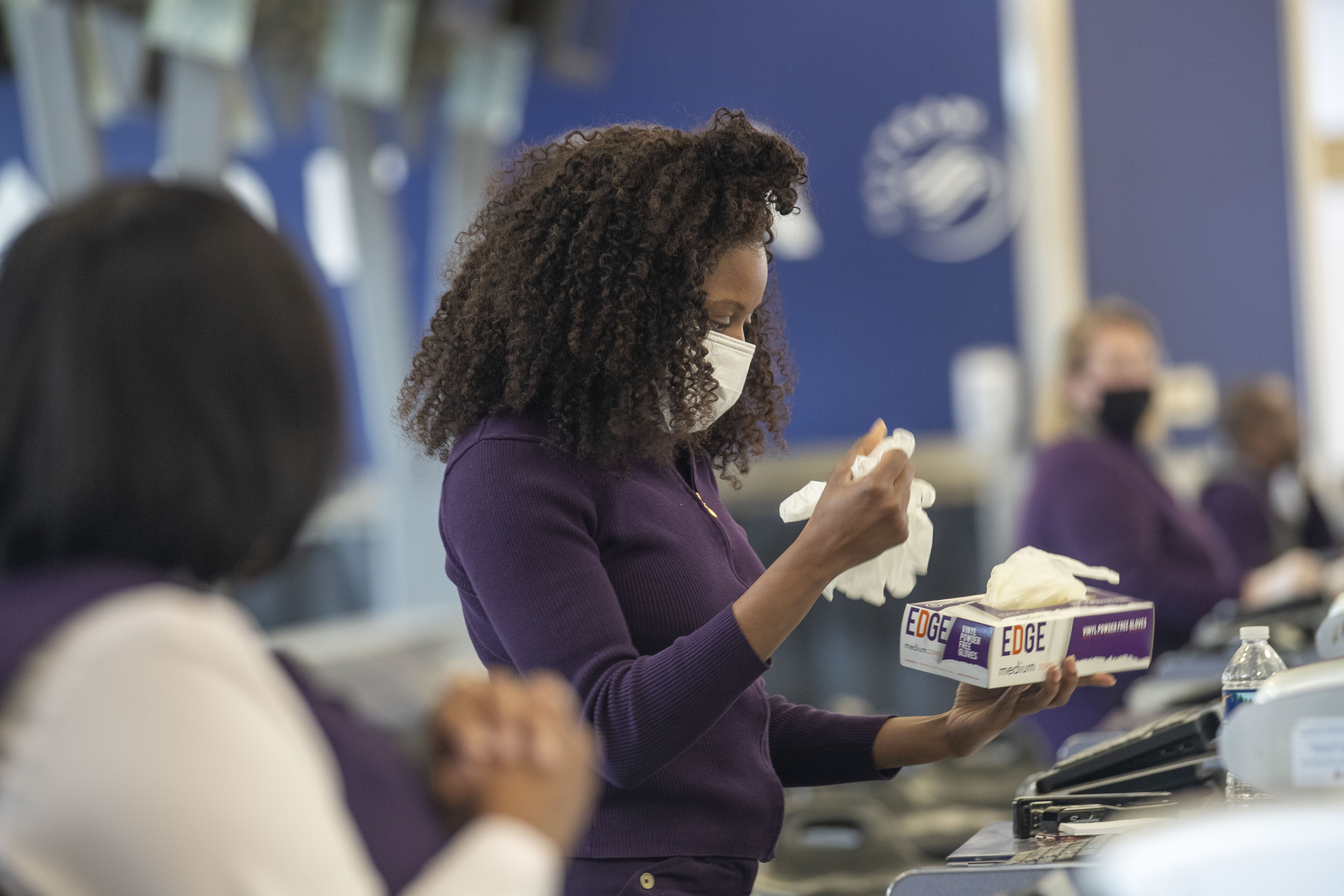 04/28/2020 - Atlanta, Georgia - Delta Air Lines customer service agent Kim Franklin retrieves a new pair of disposable gloves after working with a customer during her shift at a Delta Air Lines ticket counter inside Atlanta's Hartsfield-Jackson International Airport, Tuesday, April 28, 2020. (ALYSSA POINTER / ALYSSA.POINTER@AJC.COM)