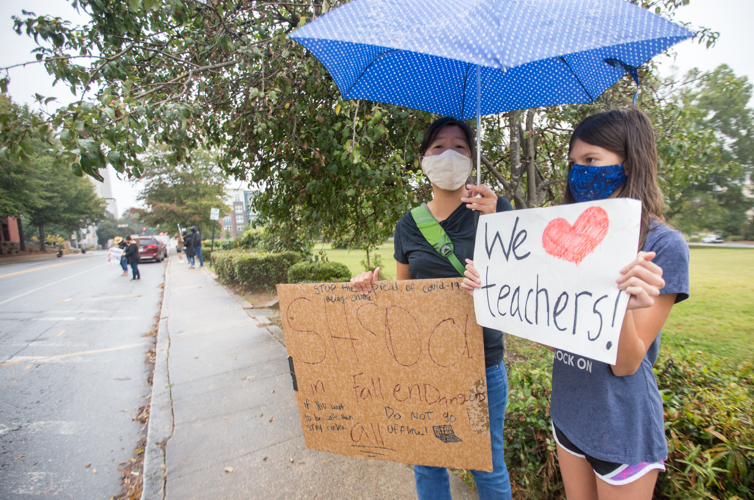 Teachers, parents and students, including Keri Chaya, left, and her daughter 10-year-old Calla Lockwood, right, protest in front of the Decatur City School Headquarters on Trinity Place in response to the district's plan to return teachers to schools in an effort to get back to in-person learning Friday, Oct, 9, 2020. (Jenni Girtman for The Atlanta Journal-Constitution)