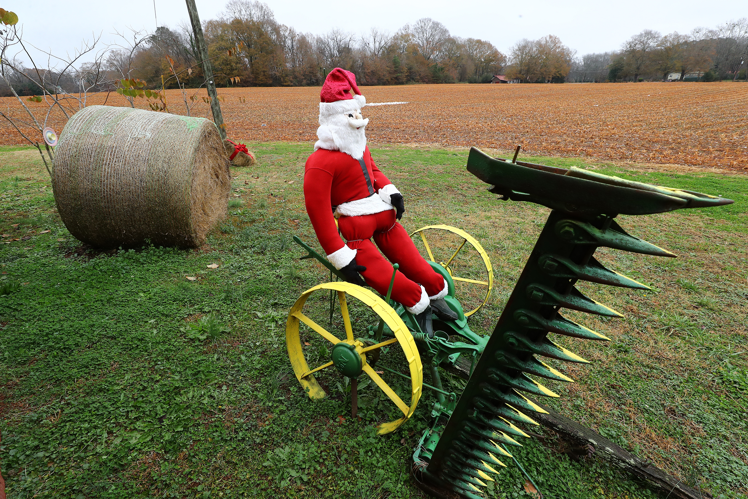 A Santa sits on an antique piece of farm equipment next to a recently harvested field along Atlanta Highway in the tiny historic town of Rutledge on Wednesday, Dec 8, 2021. “Curtis Compton / Curtis.Compton@ajc.com”`