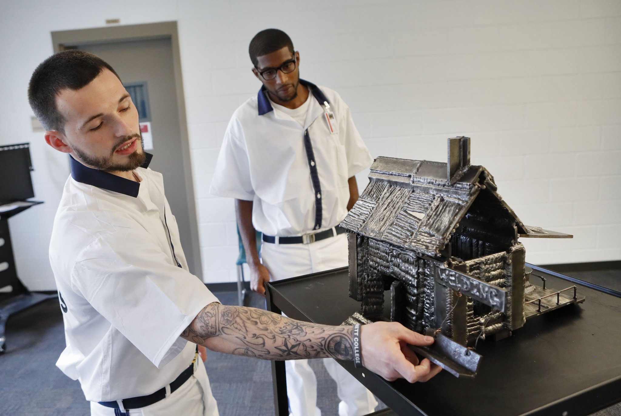Gage Bryant (left) and Christopher Wilson in July show a model house built out of steel that they constructed in their welding class. They are prisoners at the Gwinnett County Comprehensive Correctional Complex in Lawrenceville, which offered them the opportunity to learn welding. Bob Andres / bandres@ajc.com