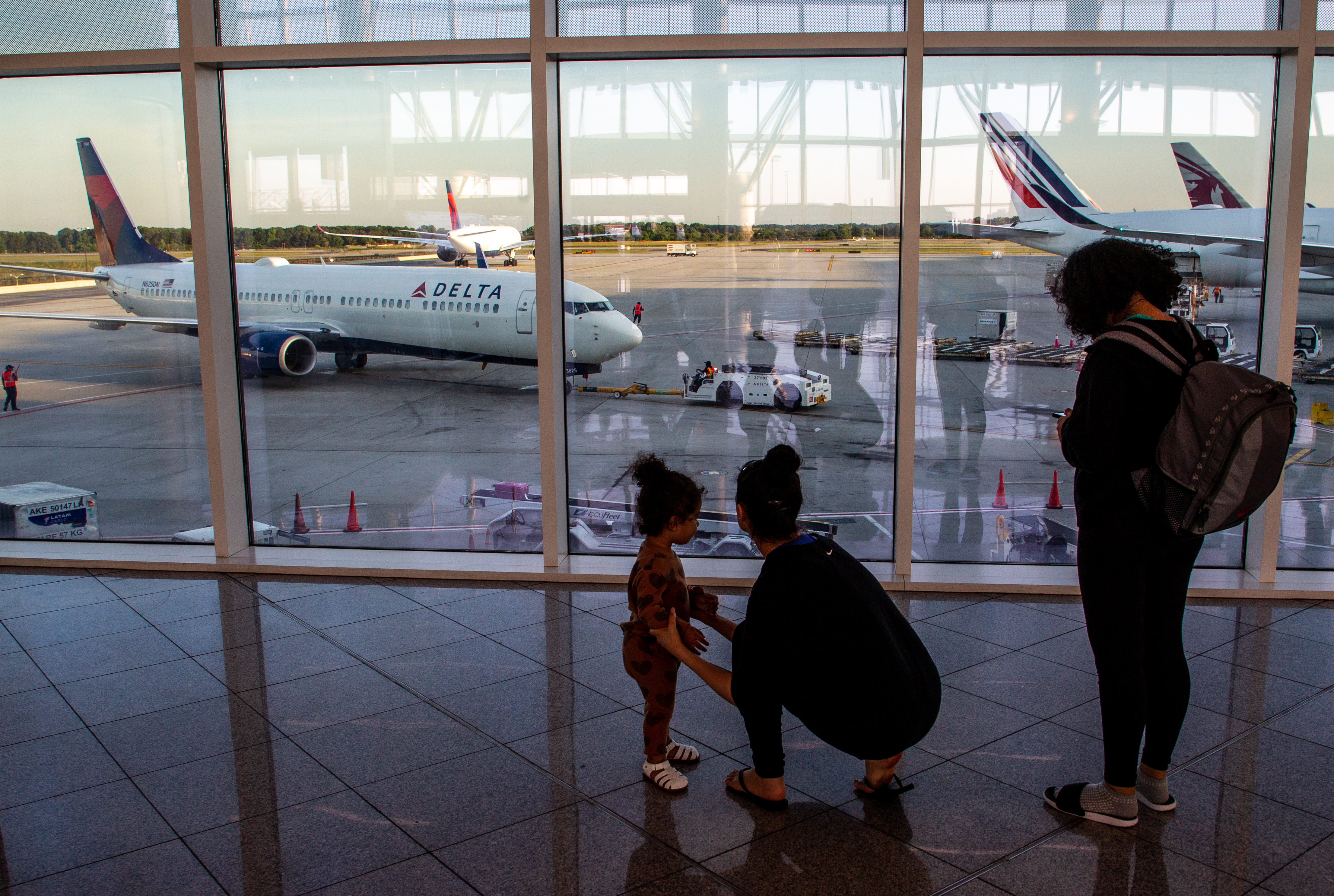 The setting sun lights up the international terminal at Hartsfield-Jackson Atlanta Airport as travelers make their way to their flight Tuesday, May 10, 2022. (Steve Schaefer / steve.schaefer@ajc.com)