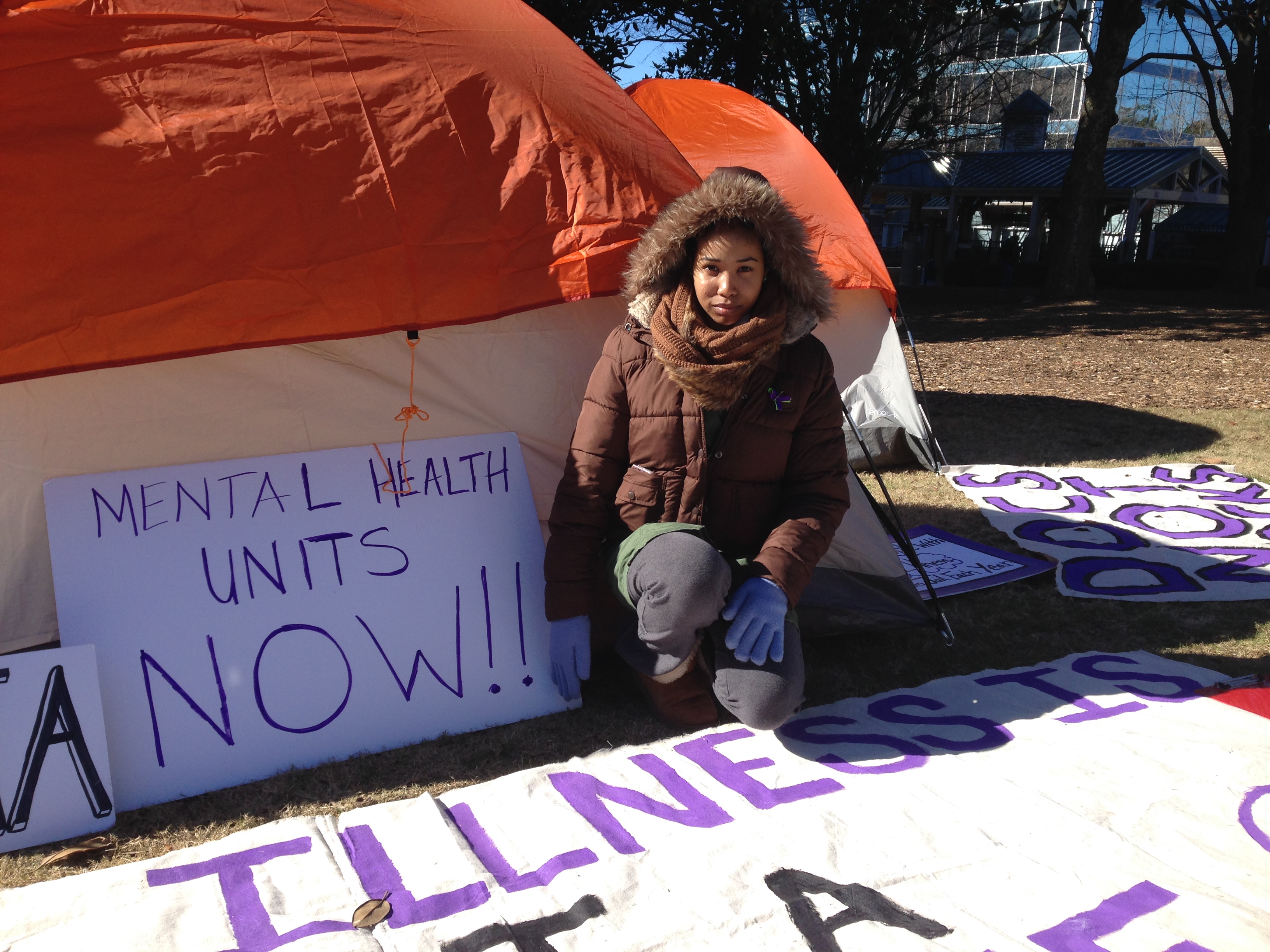 Bridget Anderson kneels at the door of one of the tents outside the DeKalb County Courthouse, where she and other activists await a grand jury decision in the death of Anthony Hill, the unarmed veteran shot and killed by police in March. Anderson was Hill’s girlfriend. GRACIE BONDS STAPLES / GSTAPLES@AJC.COM