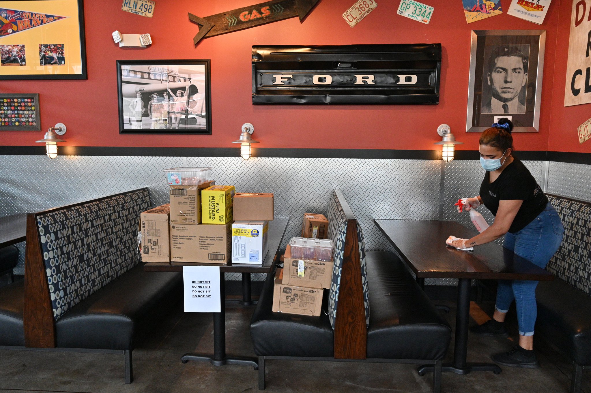 April 25, 2020 Decatur - Leah Johnson, employee, uses a disinfectant wipe to sanitize tables as restaurant staff prepare to reopen the restaurant at Bad Daddy's Burger Bar in Decatur on Saturday, April 25, 2020. On Monday, Kemp announced shuttered businesses including barbershops, beauty and nail salons, spas, gyms and bowling alleys could reopen Friday. Movie theaters and restaurant dining rooms can reopen Monday. (Hyosub Shin / Hyosub.Shin@ajc.com)