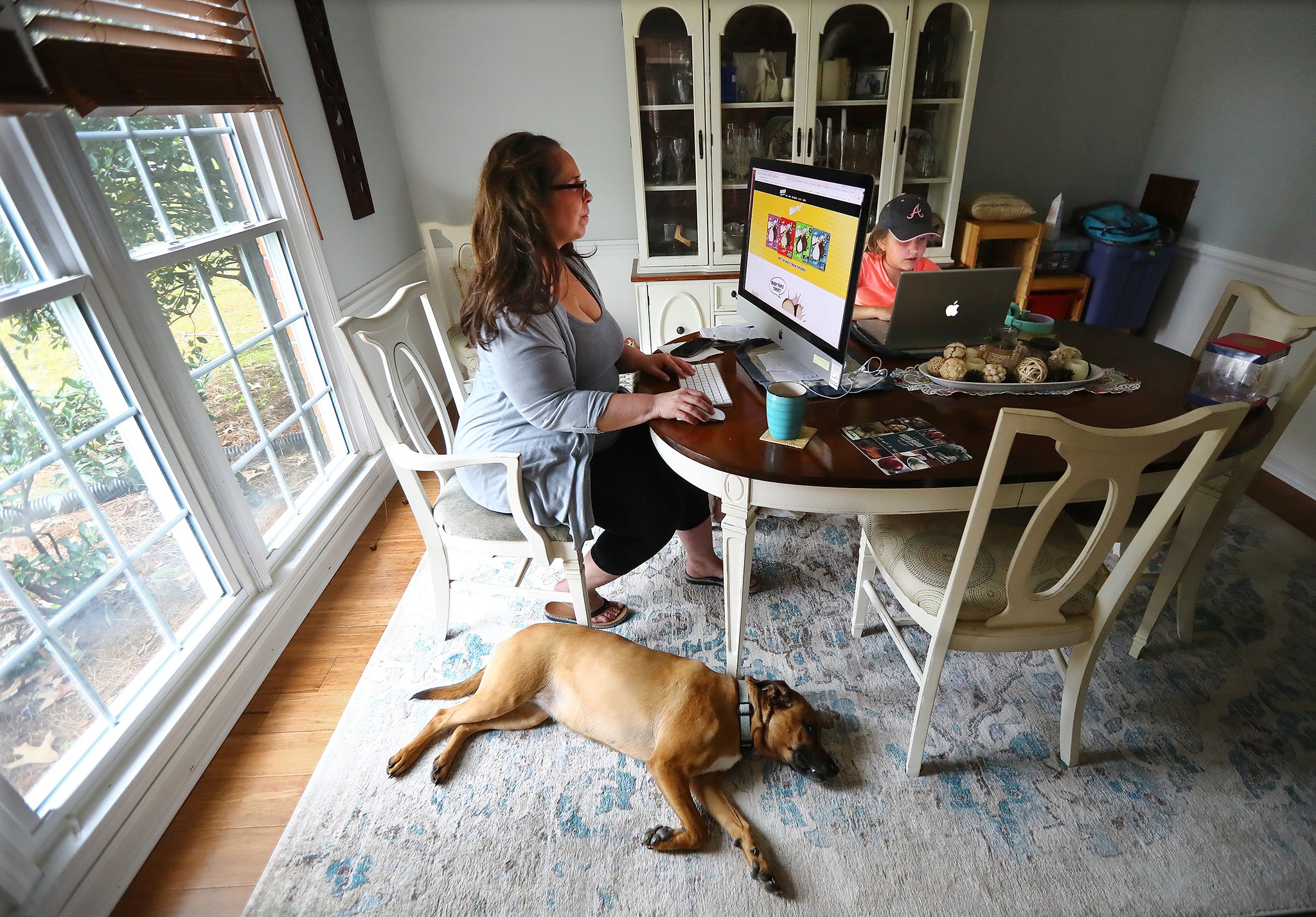 Sandra Gurley juggles decisions about branding as well as two children, working in isolation from the dining room of her Marietta home with daughter Cassidy, 8, and the family dog Tessa on Tuesday, April 7, 2020. Gurley is the director of brands for High Road Ice Cream. Her son Liam (not pictured) is 13. (Photo: Curtis Compton / ccompton@ajc.com)