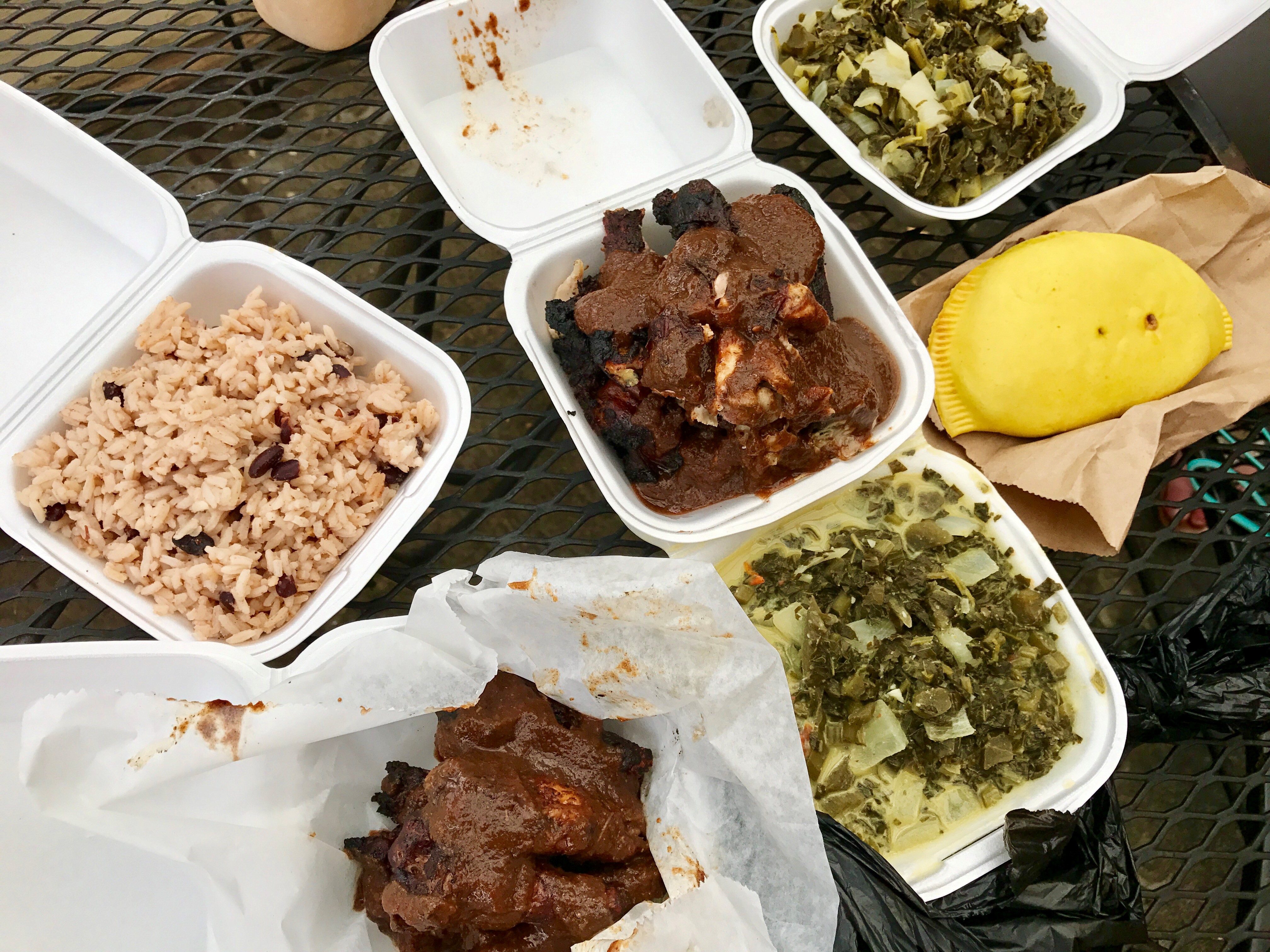 Portions at Caribbean Chicken & Fish are generous. Pictured, clockwise from left: Caribbean rice and peas, jerk chicken, collard greens, saltfish patty, callaloo, jerk wings. / Photo by Ligaya Figueras