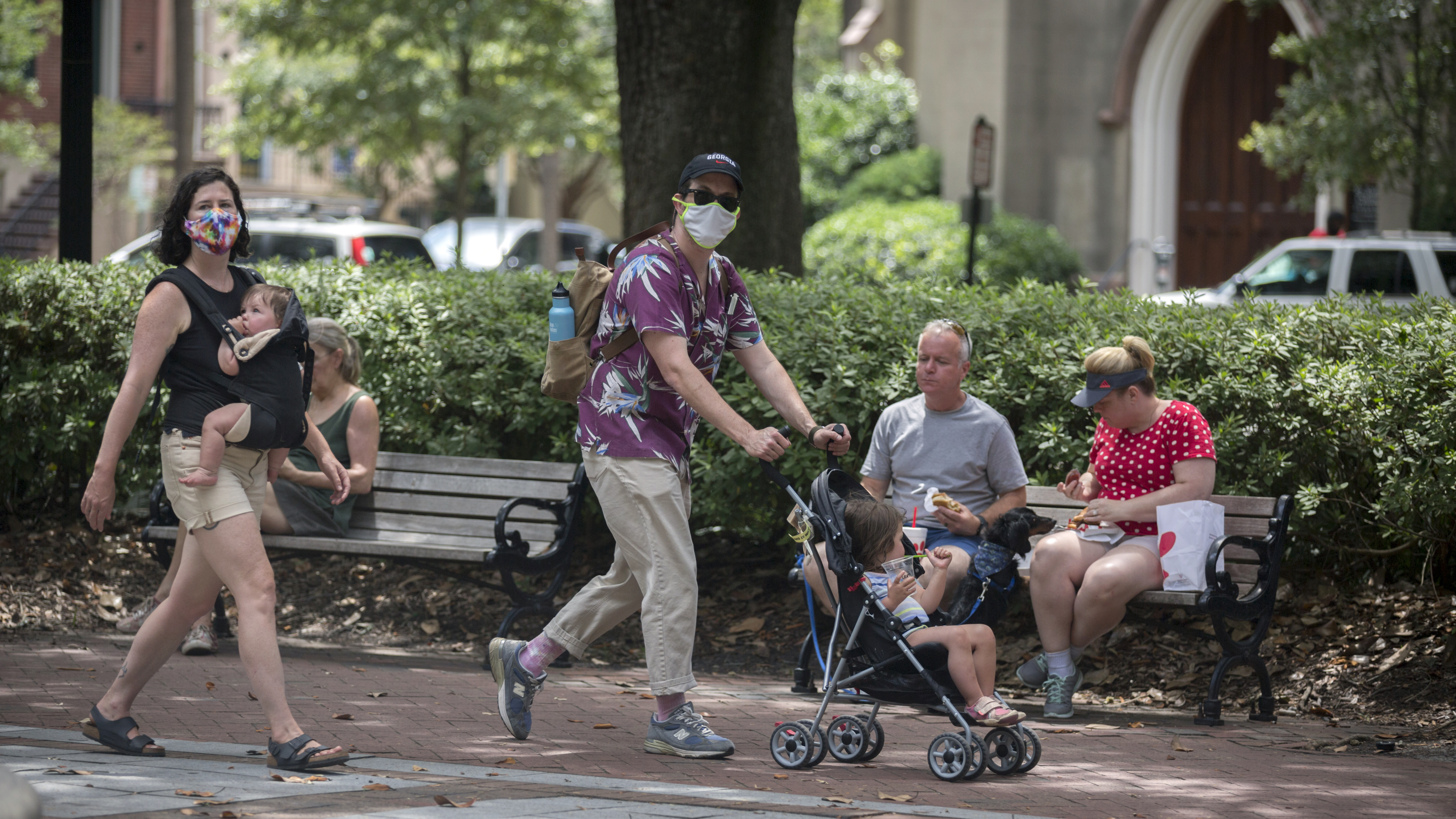 SAVANNAH, GA - June 30, 2020: A family wearing masks walk through one of Savannah's historic squares while other visitors eat on a bench near by. Savannah on Tuesday became the first major city in Georgia to require the use of face masks, setting up a potential showdown with Gov. Brian Kemp over whether local officials can take more sweeping steps than the state to contain the coronavirus. (AJC Photo/Stephen B. Morton)
