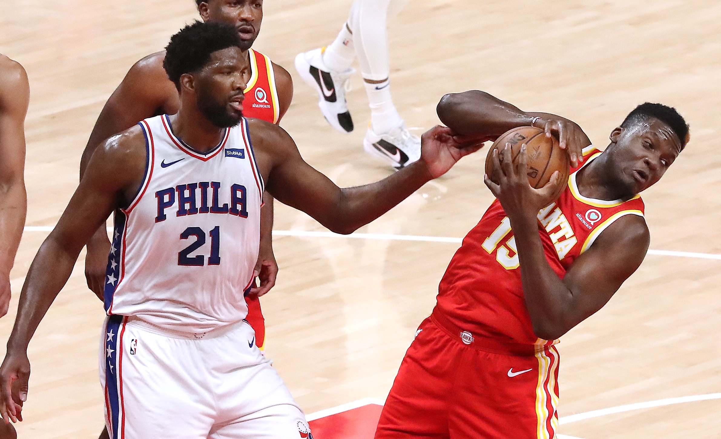 Hawks center Clint Capela grabs the defensive rebound away from Philadelphia 76ers center Joel Embiid during Game 3 of the Eastern Conference Semifinals Friday, June 11, 2021, at State Farm in Atlanta. (Curtis Compton / Curtis.Compton@ajc.com)