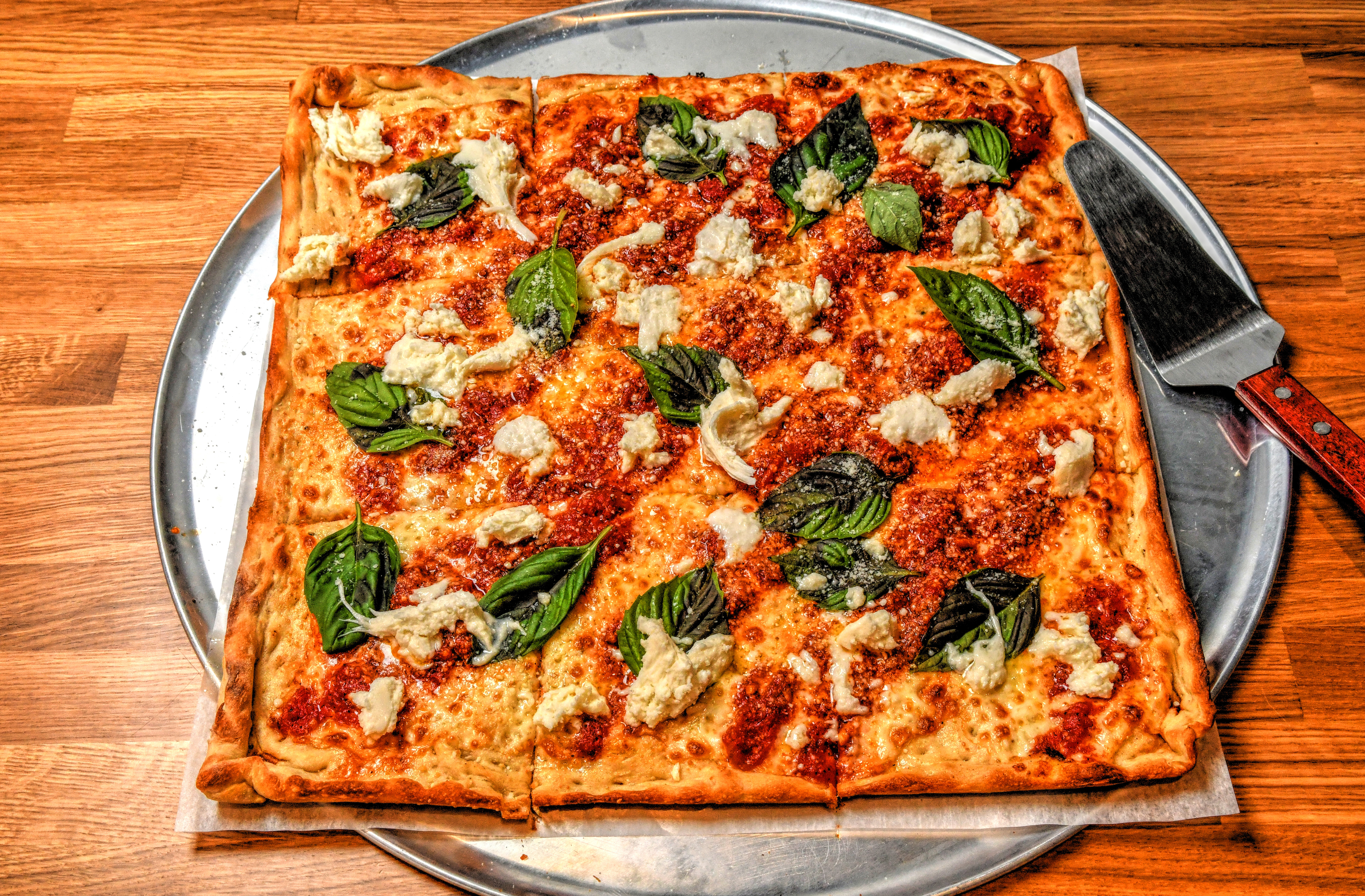 The "Noni," named after Pielands Sub & Slice owner Billy Streck's grandmother, who made this style of pizza, is one of the square pies. It features homemade marinara sauce, mozzarella, pecorino Romano and extra-virgin olive oil, finished with house-pulled fresh mozzarella and fresh basil. (Chris Hunt for The Atlanta Journal-Constitution)