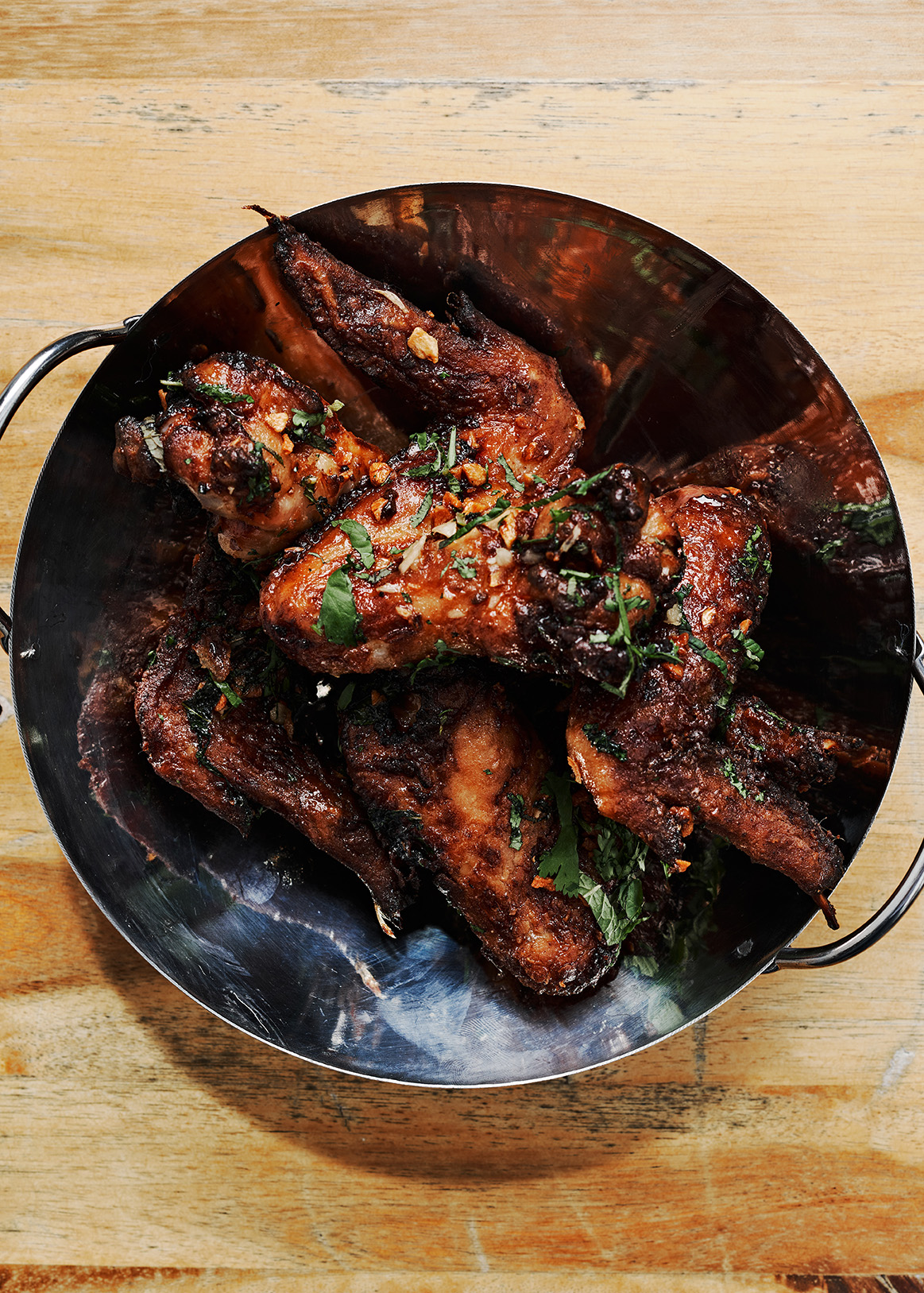 Tossed with fried garlic, mint and cilantro, Thai Sticky Wings are a recent specialty item on the menu at Tuk Tuk Thai Food Loft. / Courtesy of DeeDee Niyomkul