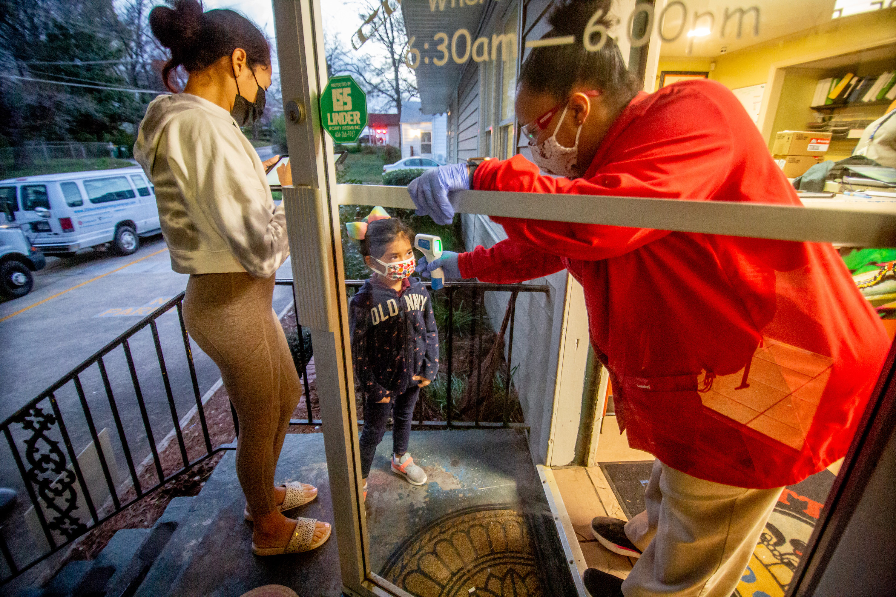 Ashley Strickland (R) takes the temperature of Isabel, 5, as her mother, Adrina Rojas, fills out the form at the Little Ones Learning Center in Forest Park Friday, March 19, 2021. STEVE SCHAEFER FOR THE ATLANTA JOURNAL-CONSTITUTION