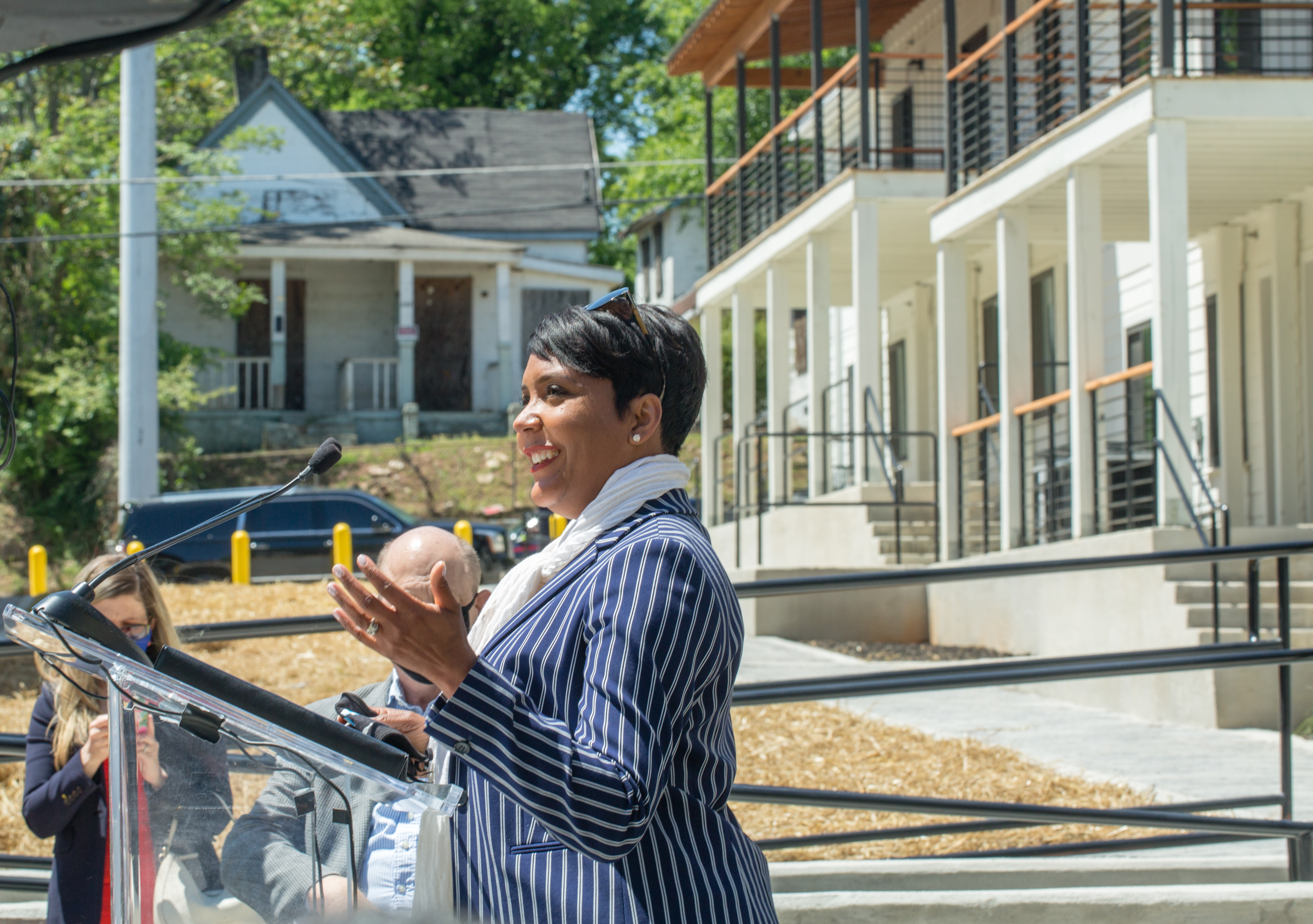 At the formal ribbon cutting of Home on The Westside, Mayor Keisha Lance Bottoms, at podium, addresses the crowd Wednesday, April 21, 2021, during the ceremony at Home on The Westside housing complex built for long-time Westside residents who need affordable housing. The house across the street from the complex is still abandoned and boarded up. (Jenni Girtman for The Atlanta Journal-Constitution)
