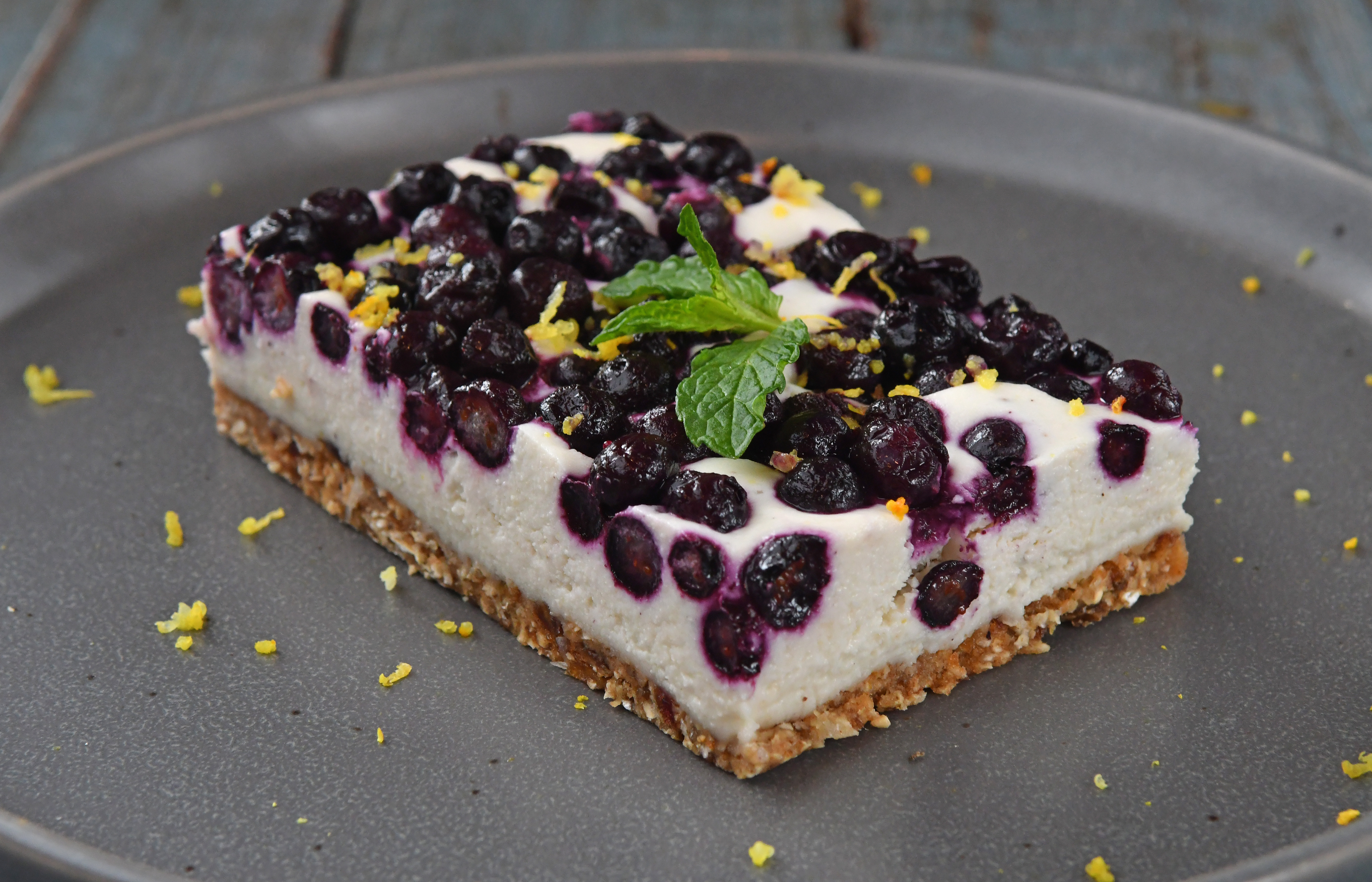 Start a new summer tradition with Blueberry Lemon Cheesecake, shown here with lemon zest and mint leaf garnish. (Styling by Claudine Molson-Sellers / Chris Hunt for the AJC)