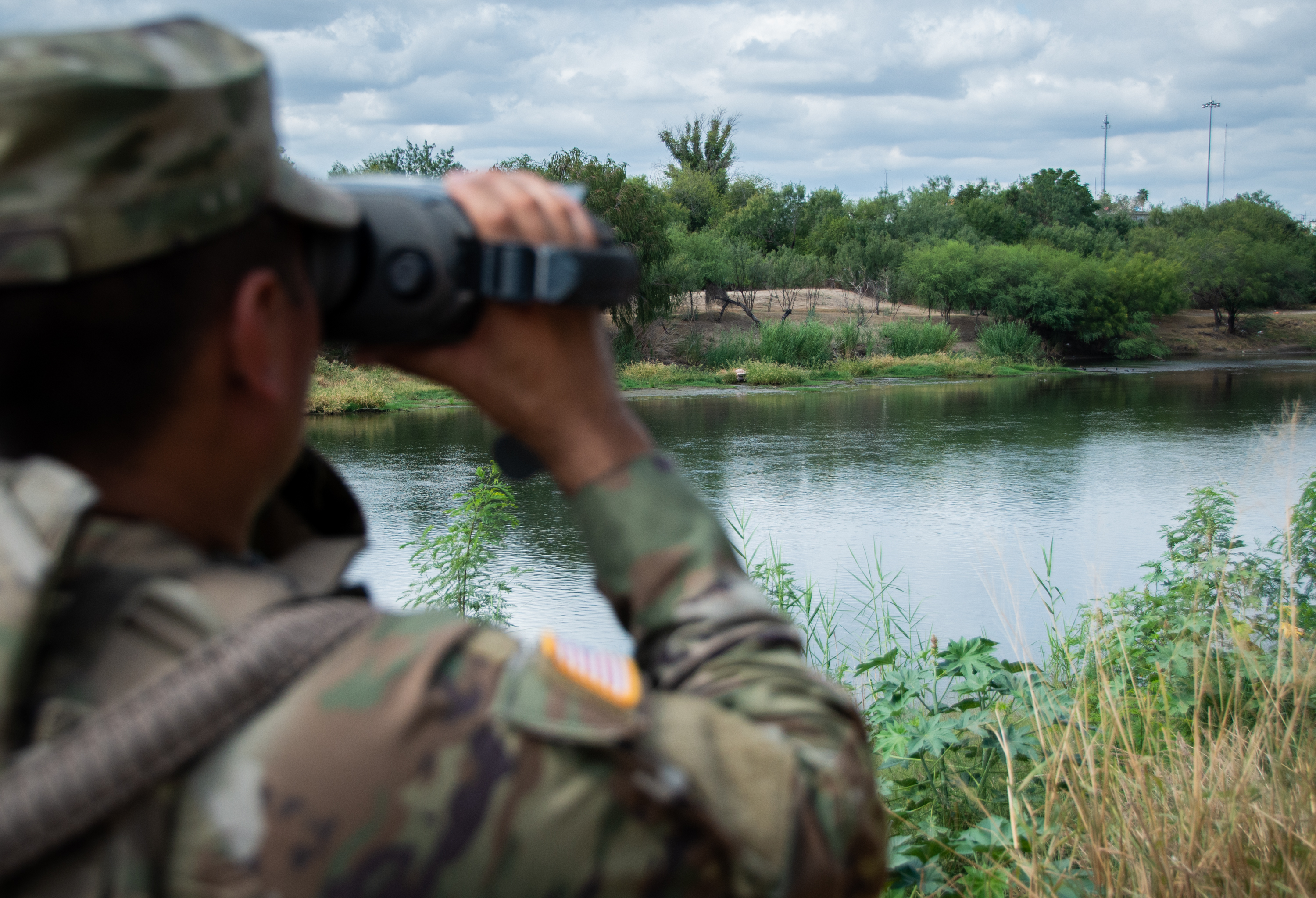 Three migrants who had managed to evade National Guard and cross the Rio  Grande onto U.S. territory wait for Border Patrol along a wall set back  from the geographical border, in El