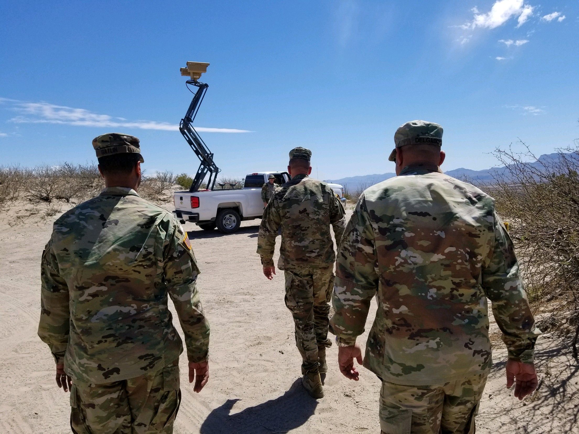 Three migrants who had managed to evade National Guard and cross the Rio  Grande onto U.S. territory wait for Border Patrol along a wall set back  from the geographical border, in El