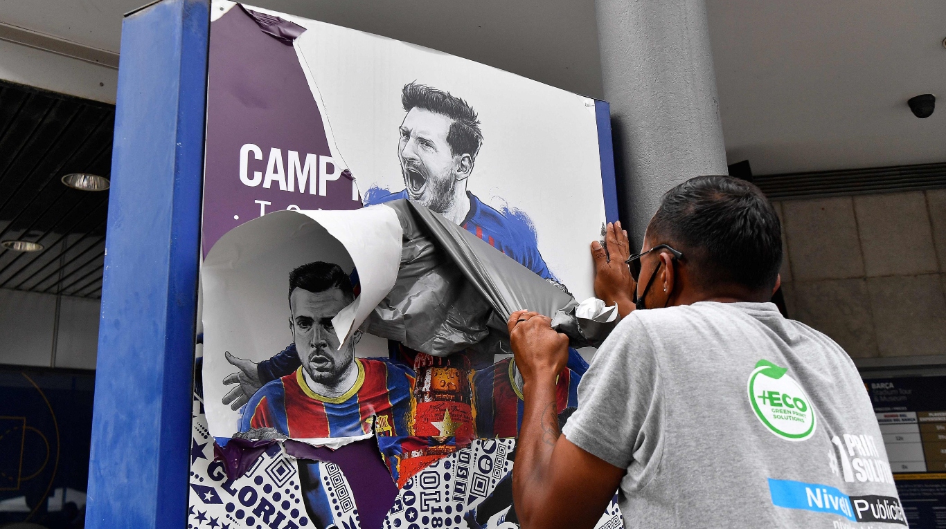 Un trabajador retira carteles de Barcelona con la foto de Messi (Foto de Pau BARRENA / AFP).