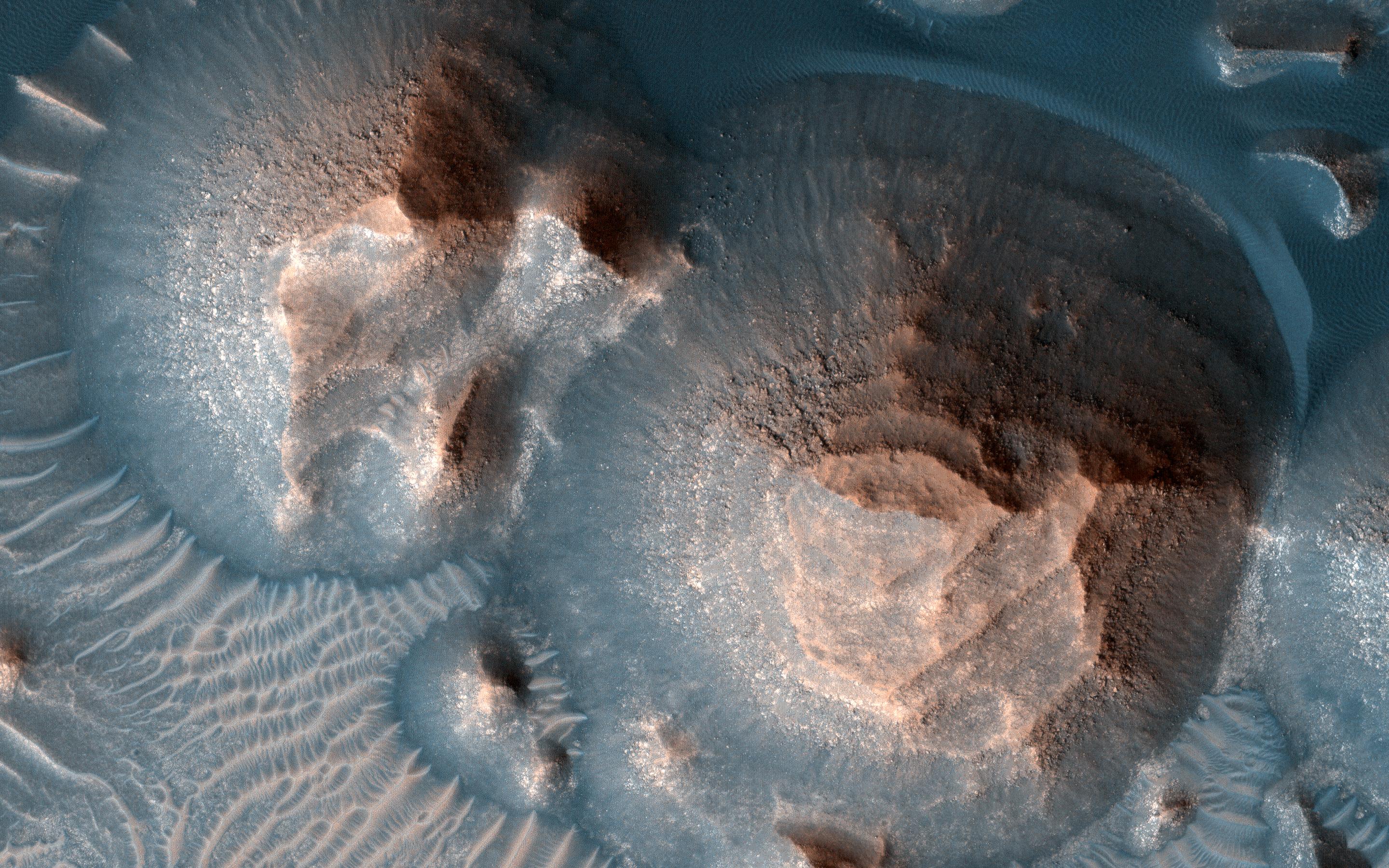 Esta imagen muestra varios cráteres en Arabia Terra llenos de capas de roca que podrían haberse formado a partir de arena o cenizas volcánicas.