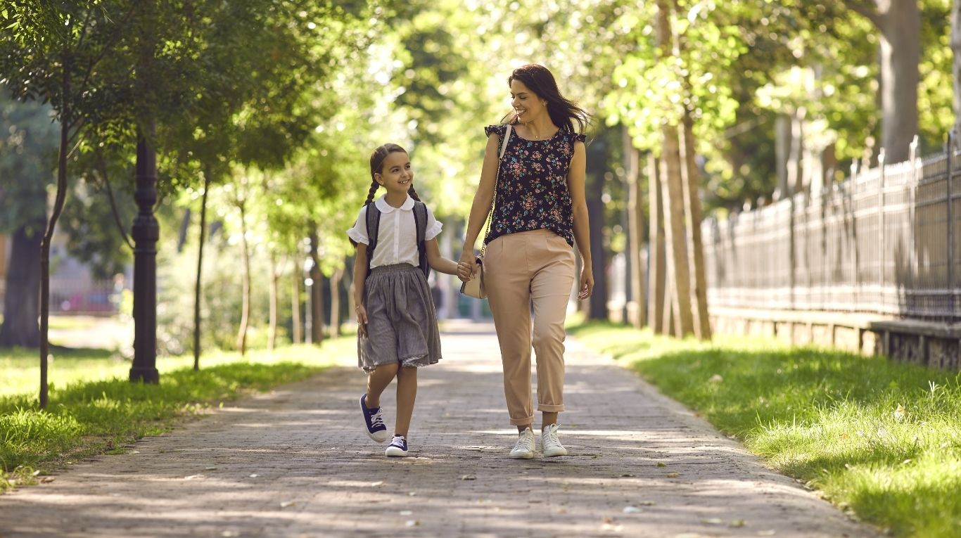 Madre junto a su hija, caminando al colegio. Foto: Adobe Srock