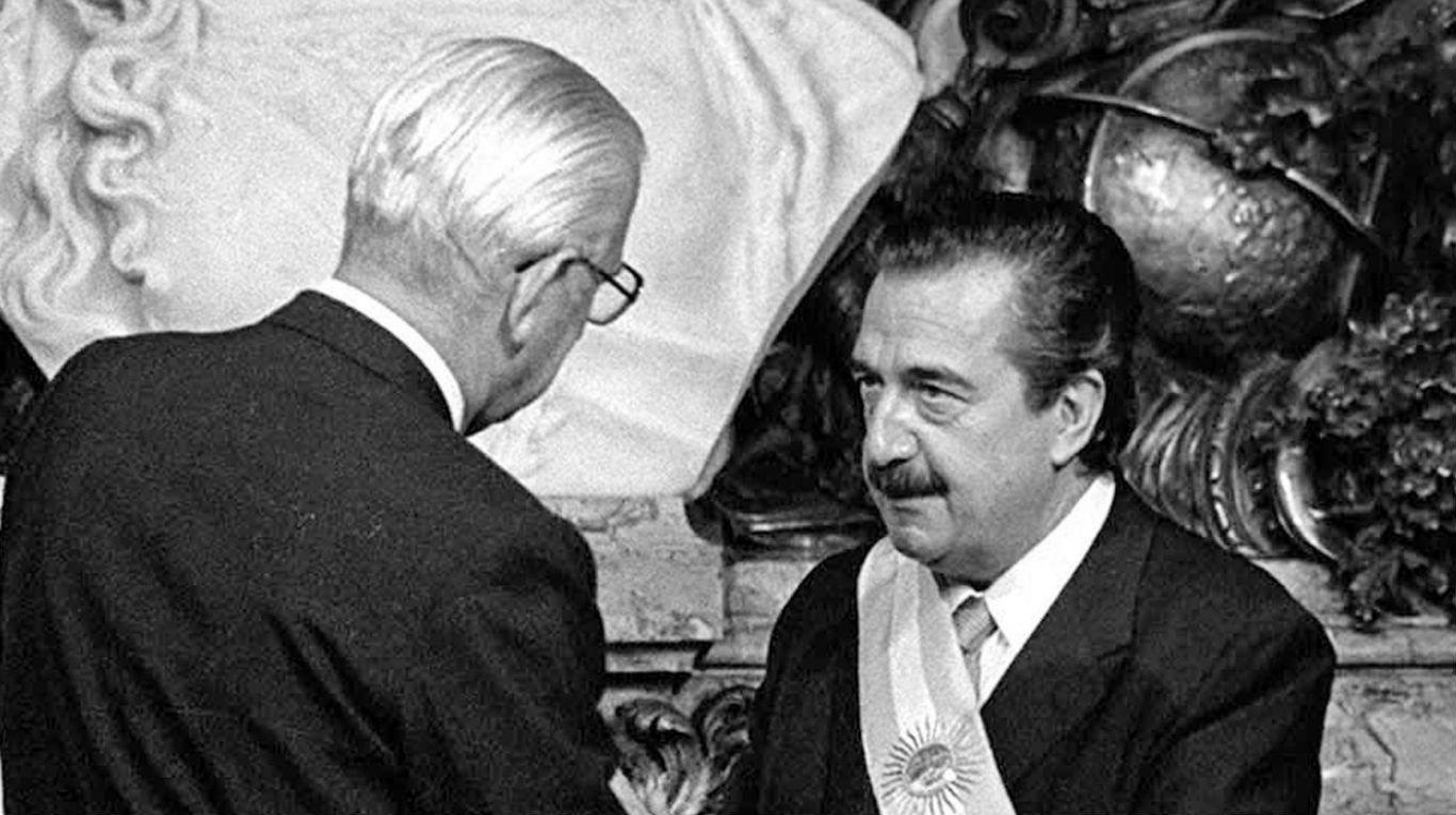 Raúl Alfonsín recibe los atributos del mando de manos del dictador Bignone.