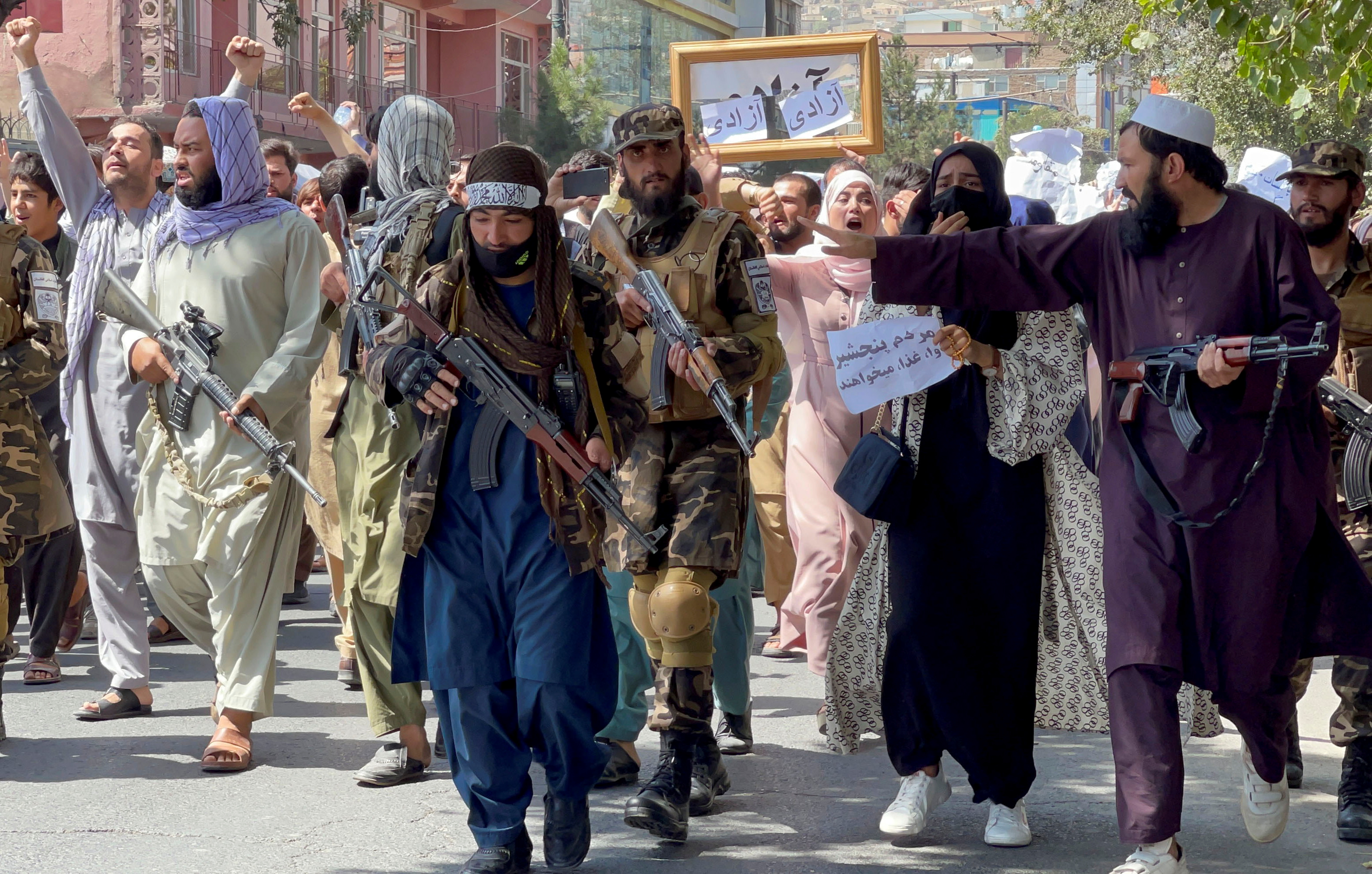 Fuerzas talibanes caminan frente a manifestantes durante una marcha cerca de la embajada de Pakistán. Fuente: REUTERS/Stringer