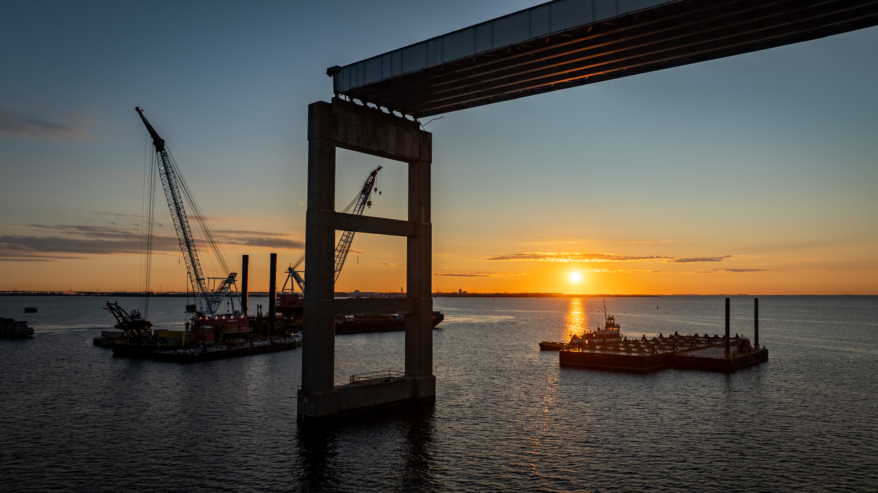Crane barges are seen at the Francis Scott Key Bridge site at sunrise as test piles are installed into the Patapsco River bed to test the strength and stability for the new bridge's foundation.