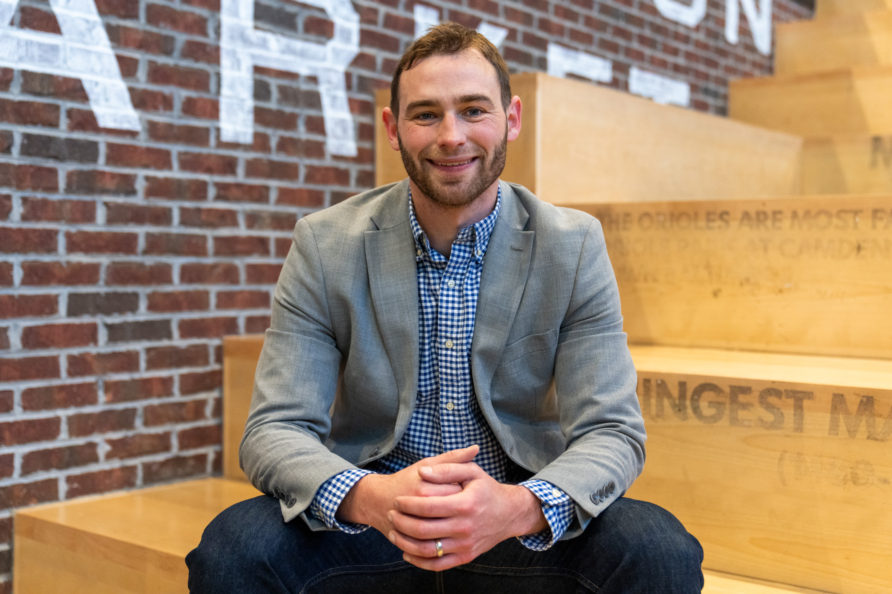 Zac Blanchard smiles for a portrait while sitting on the steps of Lexington Market.