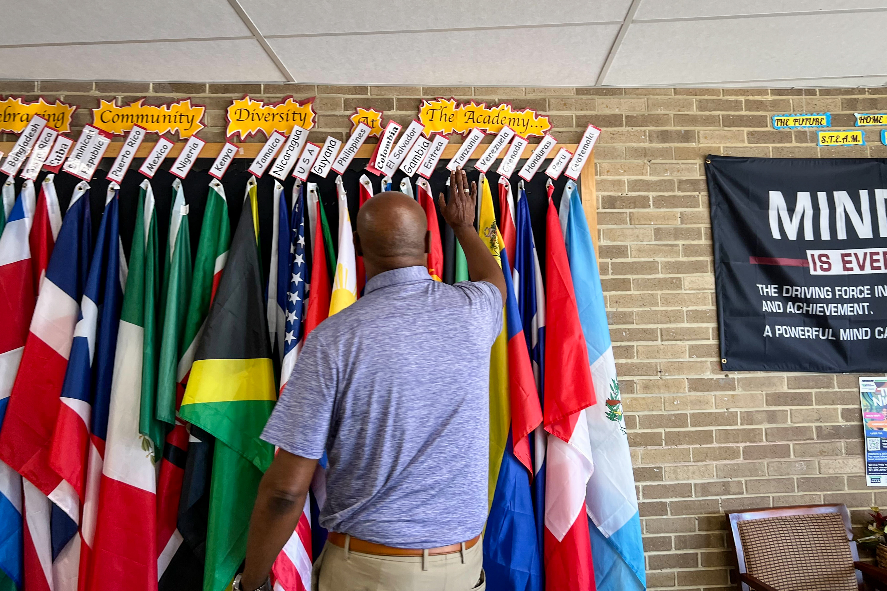 Andrew Jackson Academy Principal Warren Tweedy shows off hallway flags representing the home countries of his students and their families.