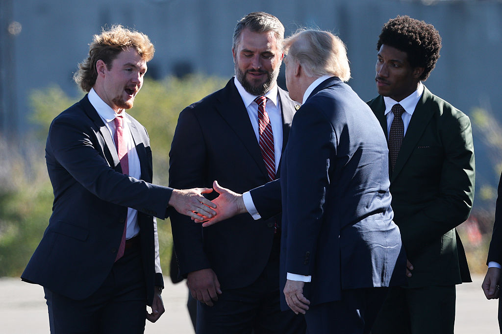 President Donald Trump  greets members of the Baltimore Ravens, from left to right, punter Ryan Eckley, long snapper Nick Moore and cornerback Marlon Humphrey, as he arrives to speak at Tradepoint Atlantic.