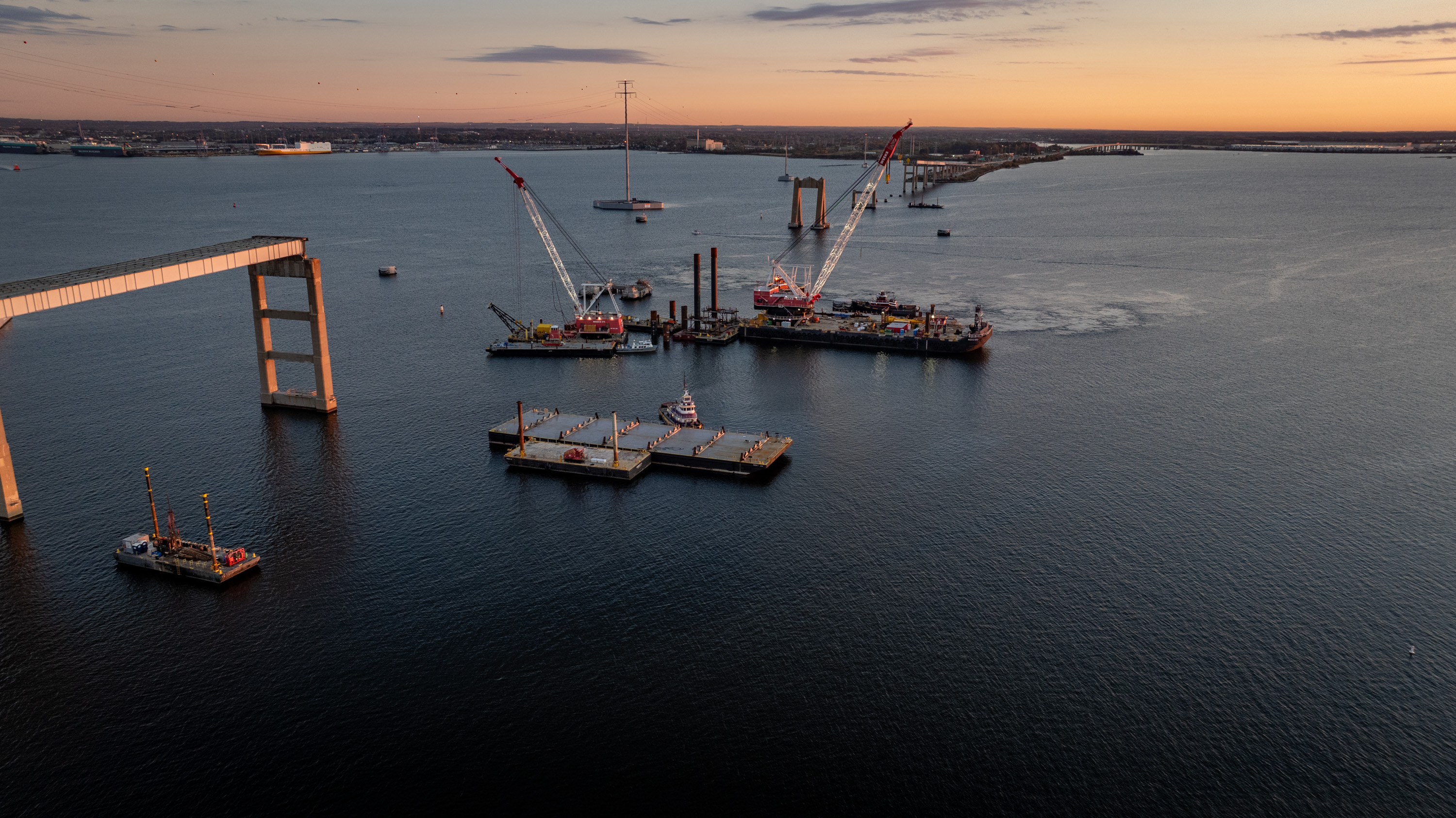 Crane barges are seen at the Francis Scott Key Bridge site at sunrise as test piles are installed into the Patapsco River bed to test the strength and stability for the new bridge's foundation.
