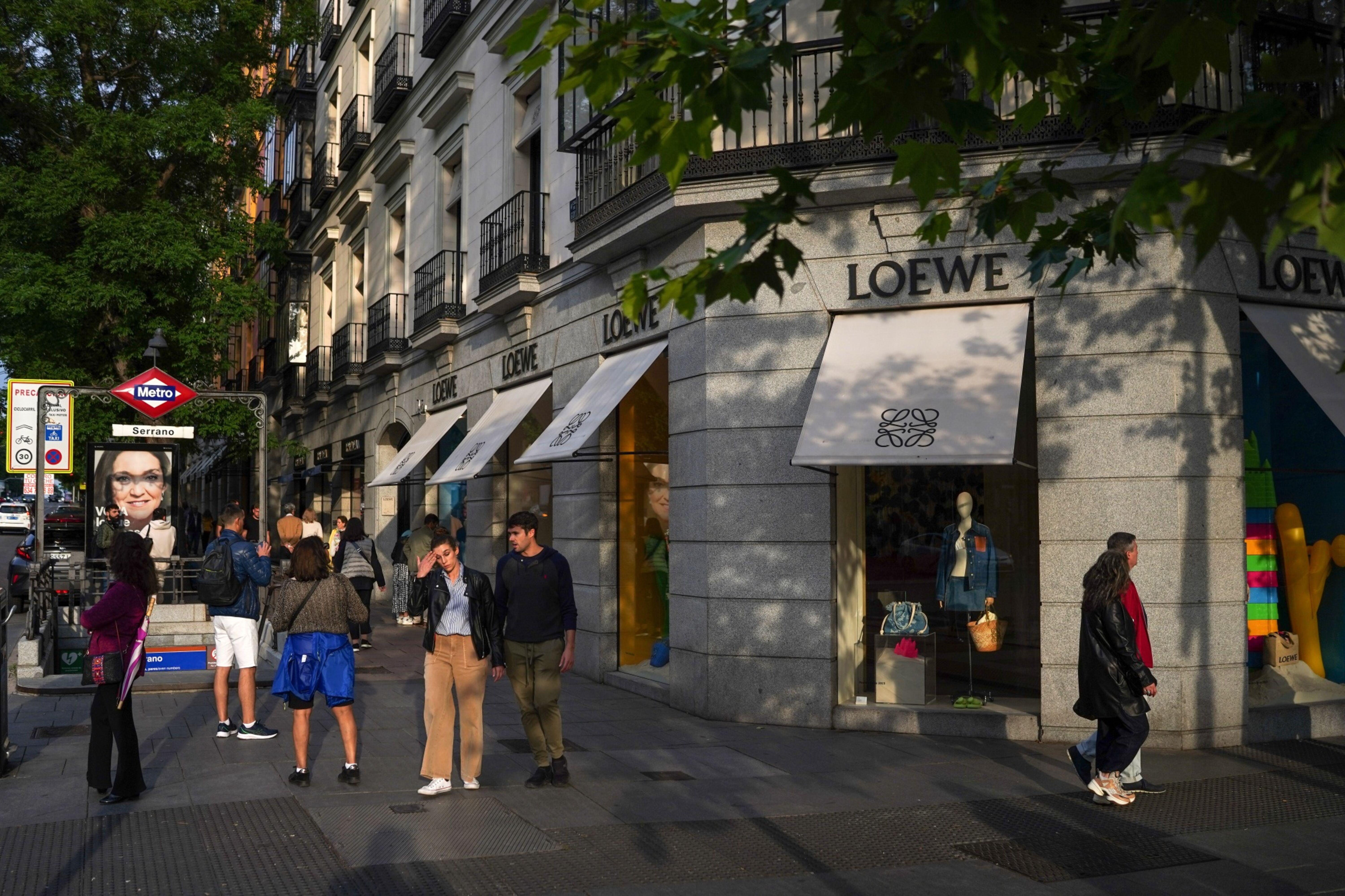 A pedestrian passes advertisements outside the Loewe SA luxury