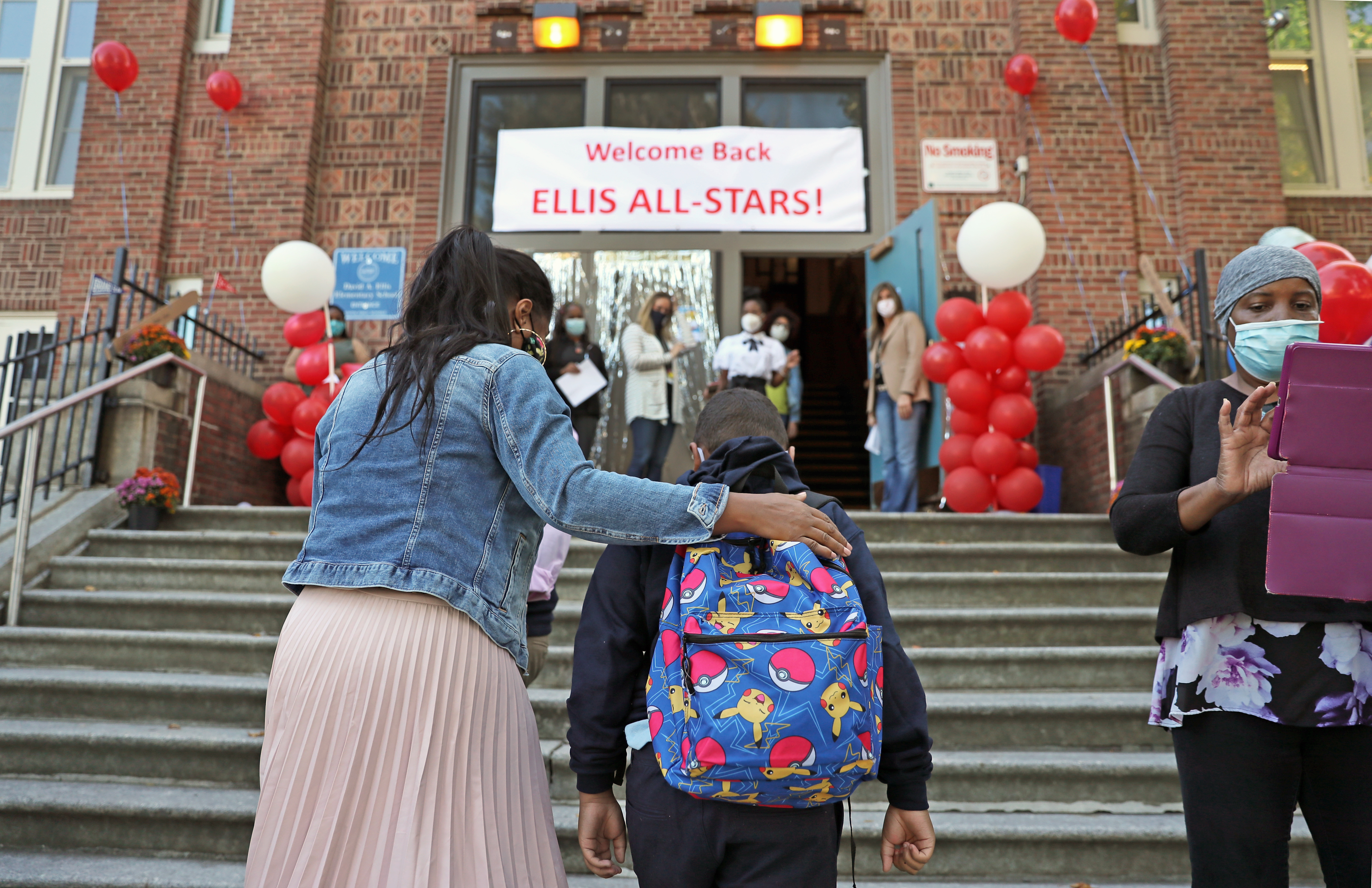 Jaiden Rosado, right, a fourth grade student, was greeted by Linda Cruz, left, on the steps of the Ellis Elementary School in Roxbury.