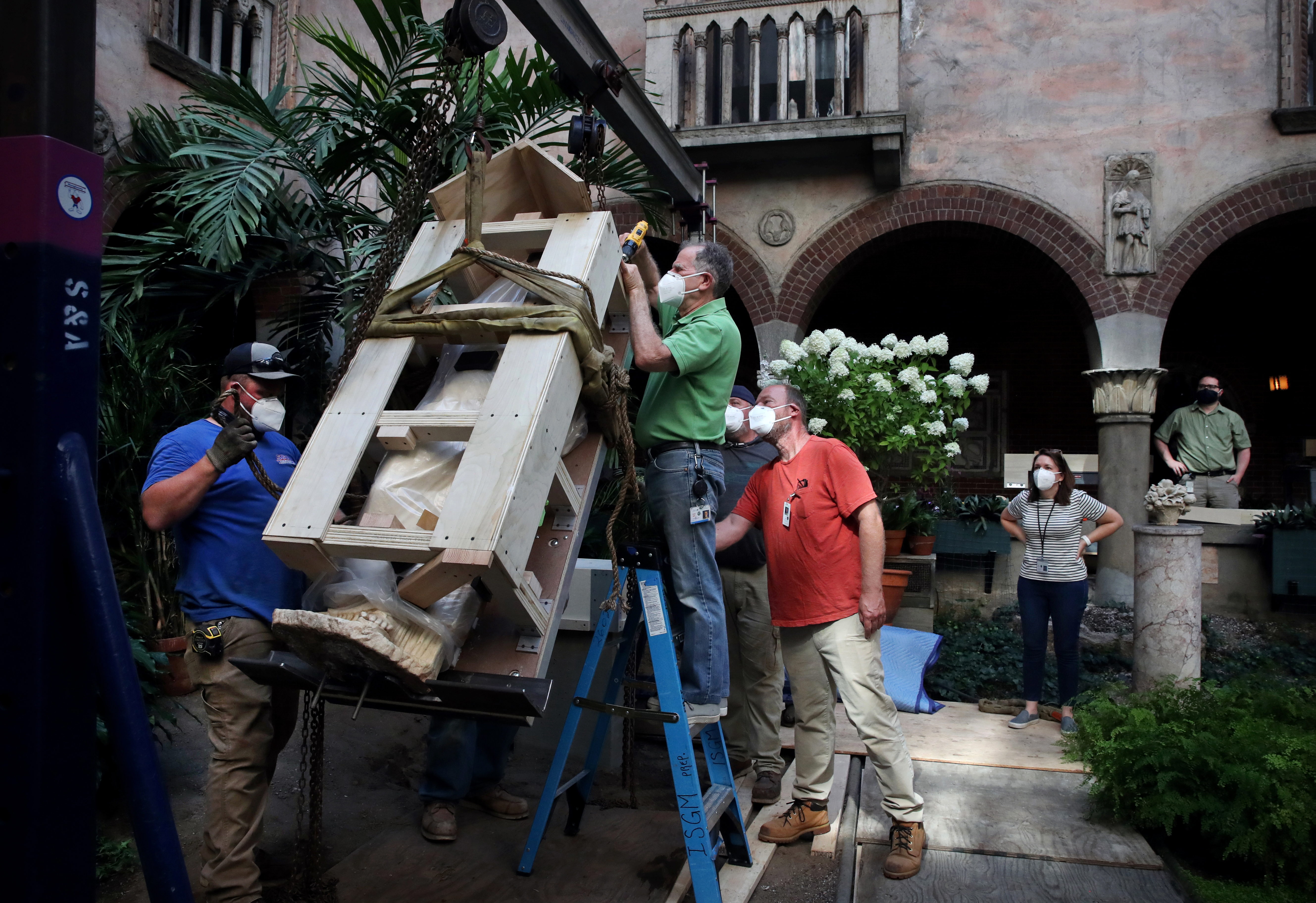 Preparator David Kalan removes some of the protective housing while a team of experts hoists the statue into position.