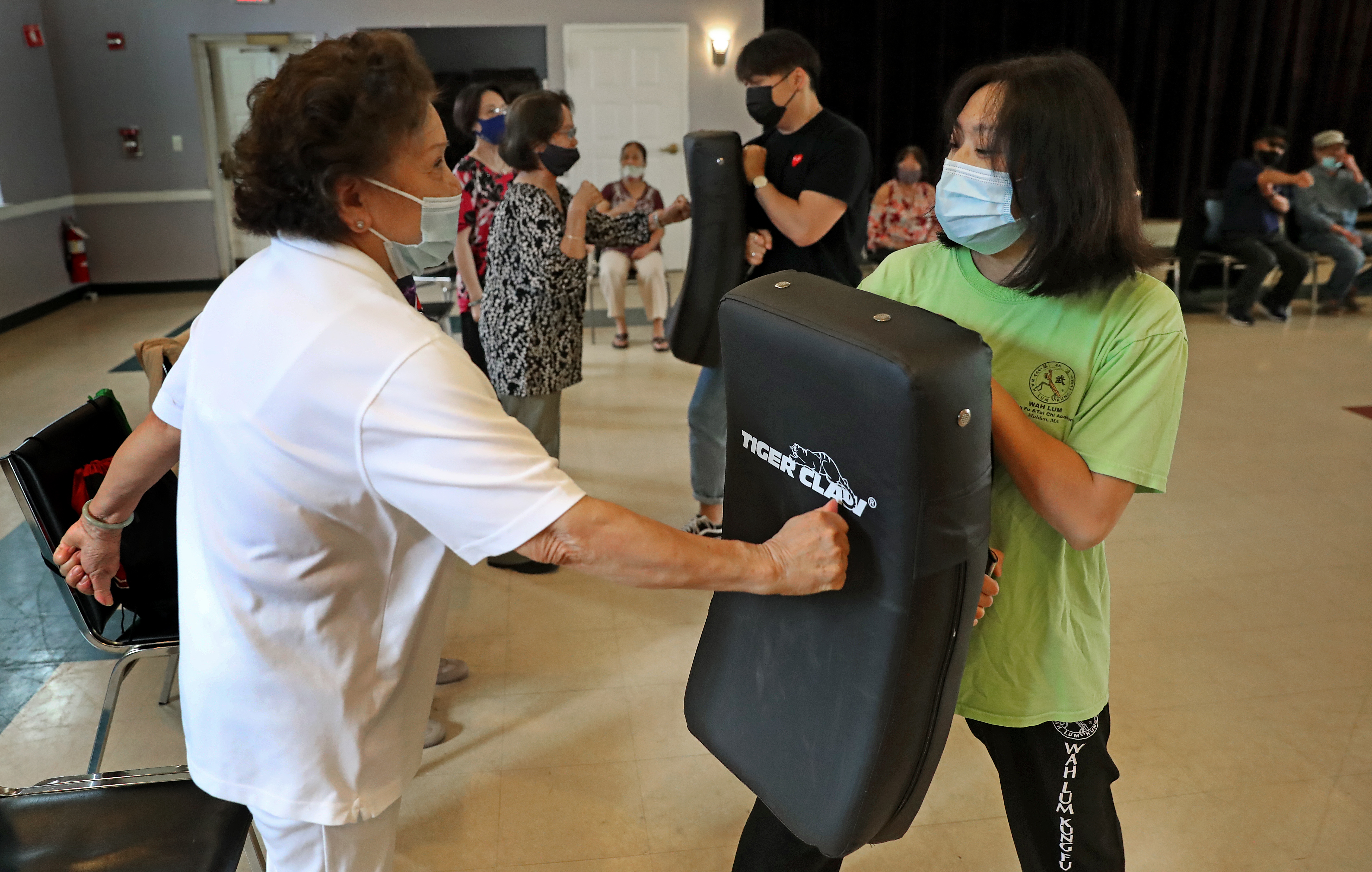 Linh Mat, 88, threw a punch during a demonstration on how to hit an attacker at VietAID's community center in Fields Corner, as instructor Mai Du (right) held the pad. Du is teaching seniors self-defense in response to a rash of assaults on older Asian Americans in many cities.