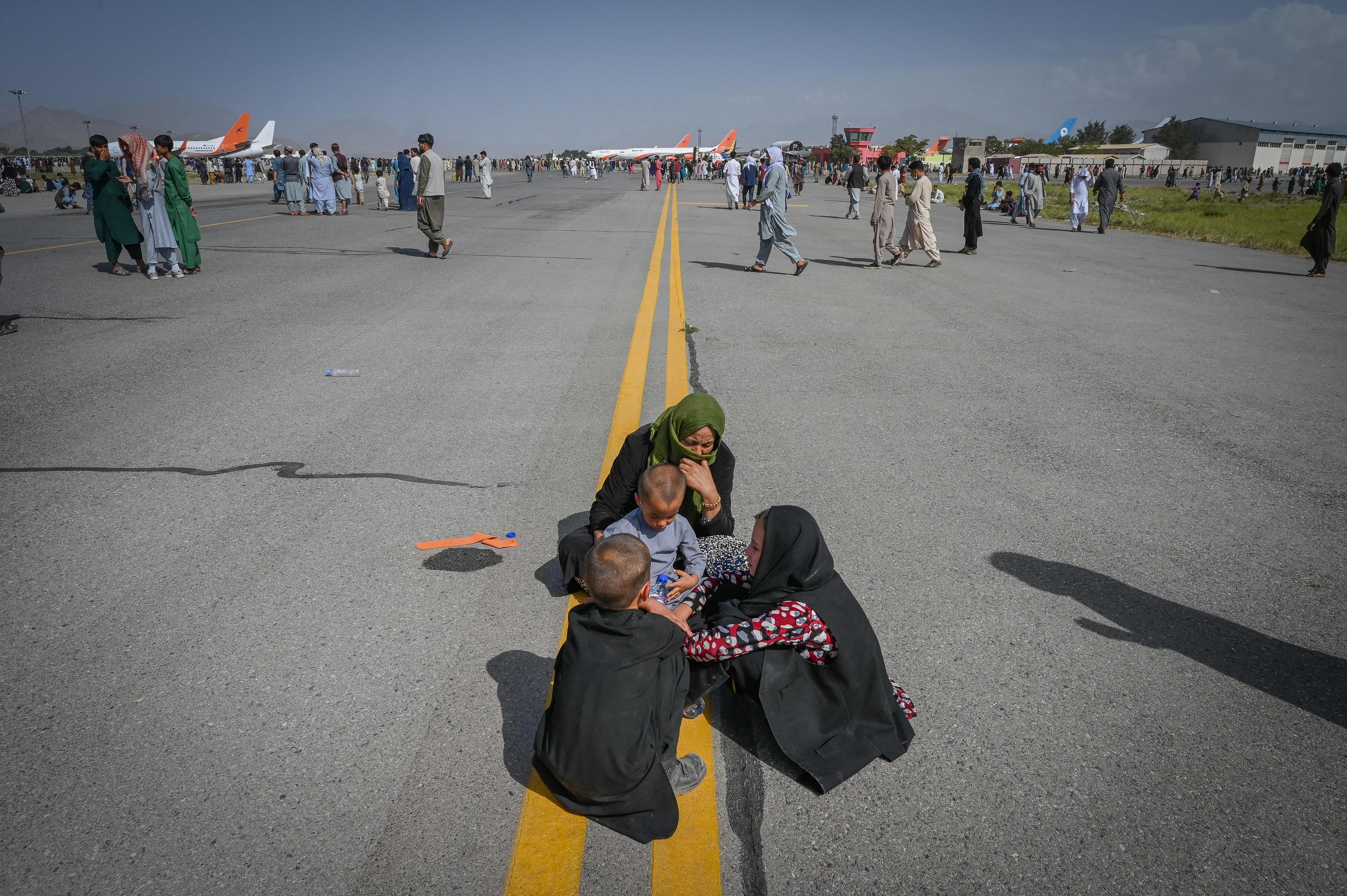 Afghan people sat along the tarmac as they waited to leave the Kabul airport.
