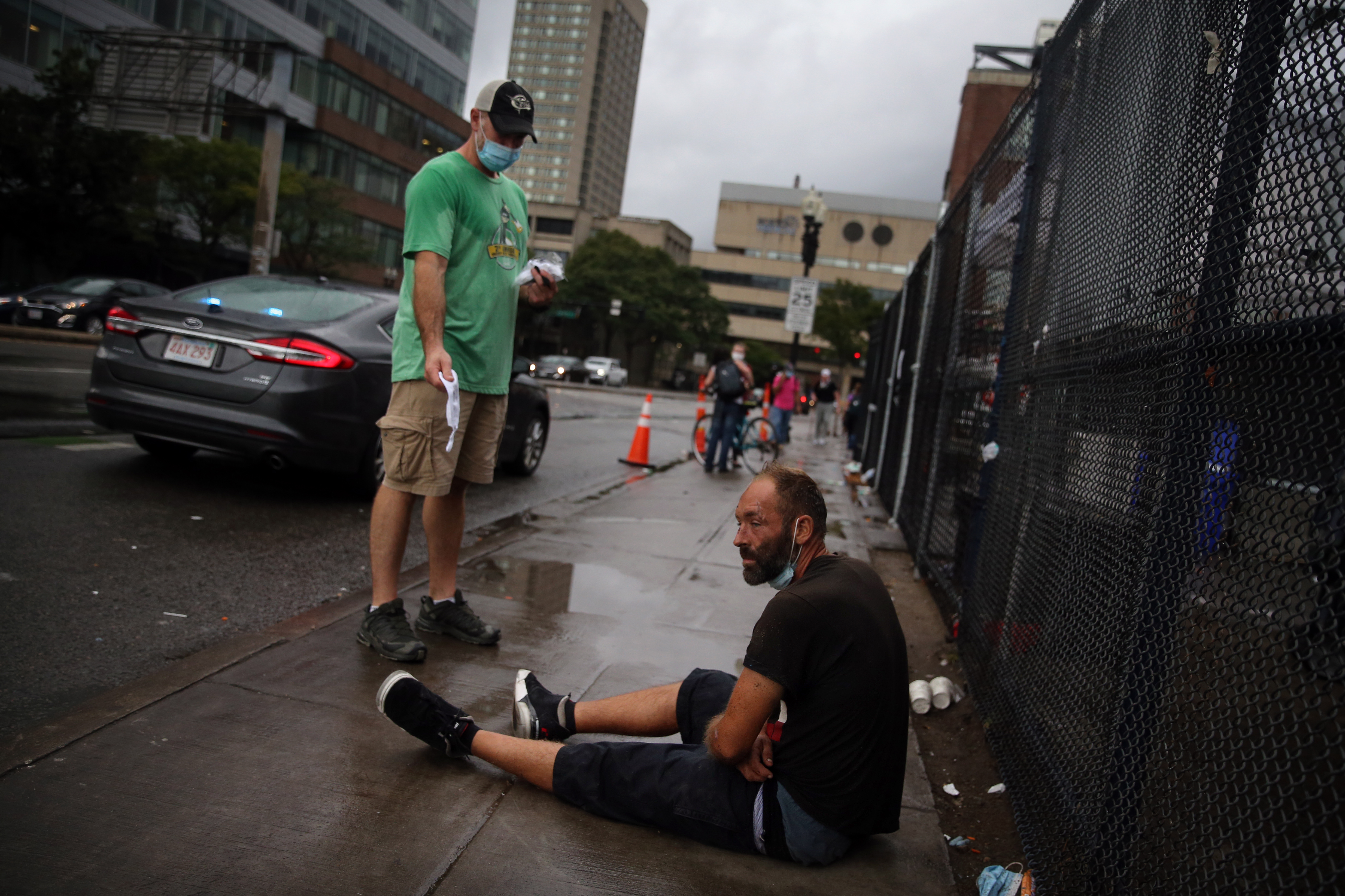 Officer Josh DeLisle, left, of the Boston Police Department Street Outreach Unit offered a fresh mask to a man sitting outside a "comfort station" run by the Boston Public Health Commission.