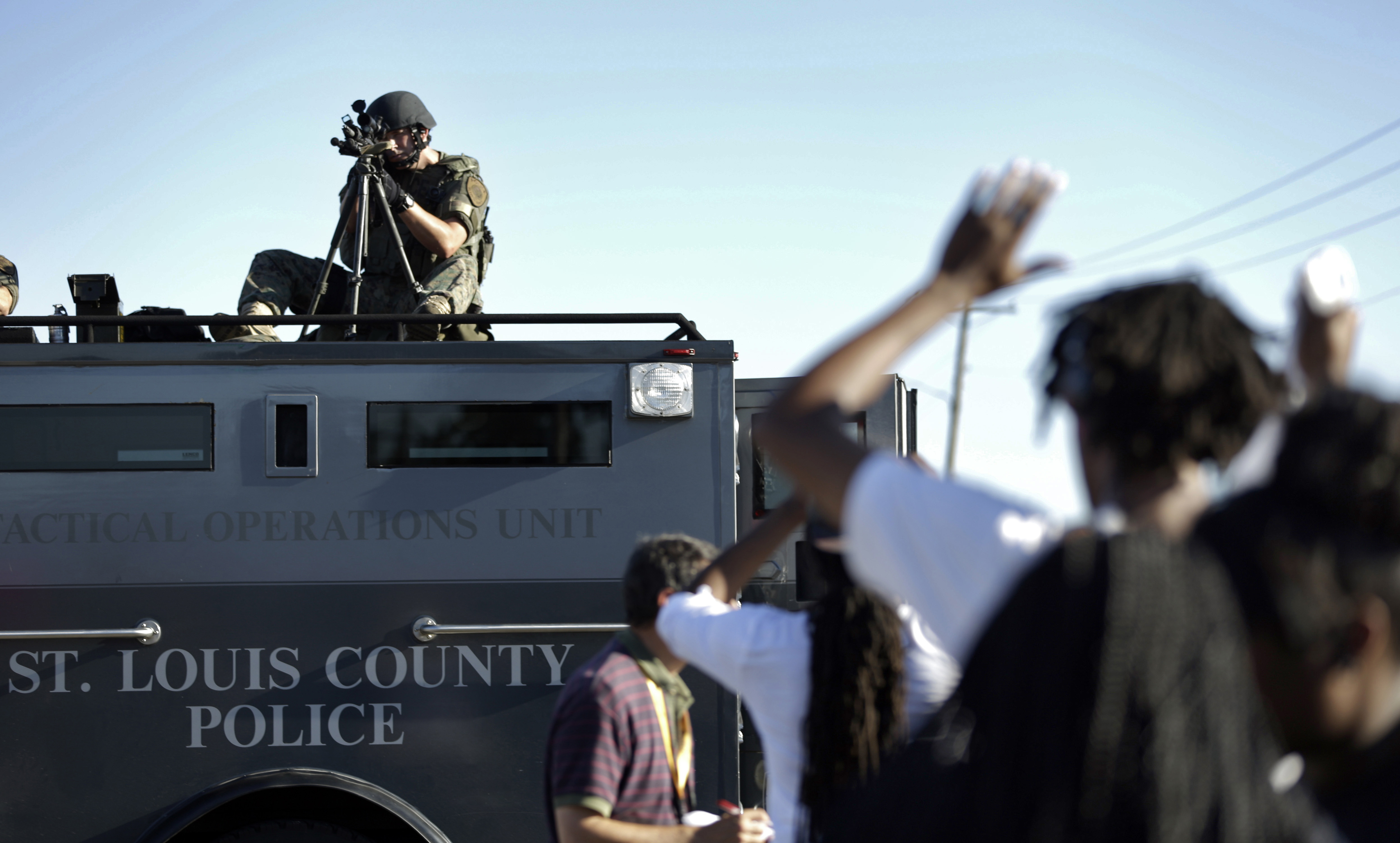 A member of the St. Louis County Police Department points his weapon in the direction of a group of protesters in Ferguson, Mo., on Aug. 13, 2014. On Aug. 9, 2014, a white police officer fatally shot Michael Brown, a Black teenager, in the St. Louis suburb, sparking protests.
