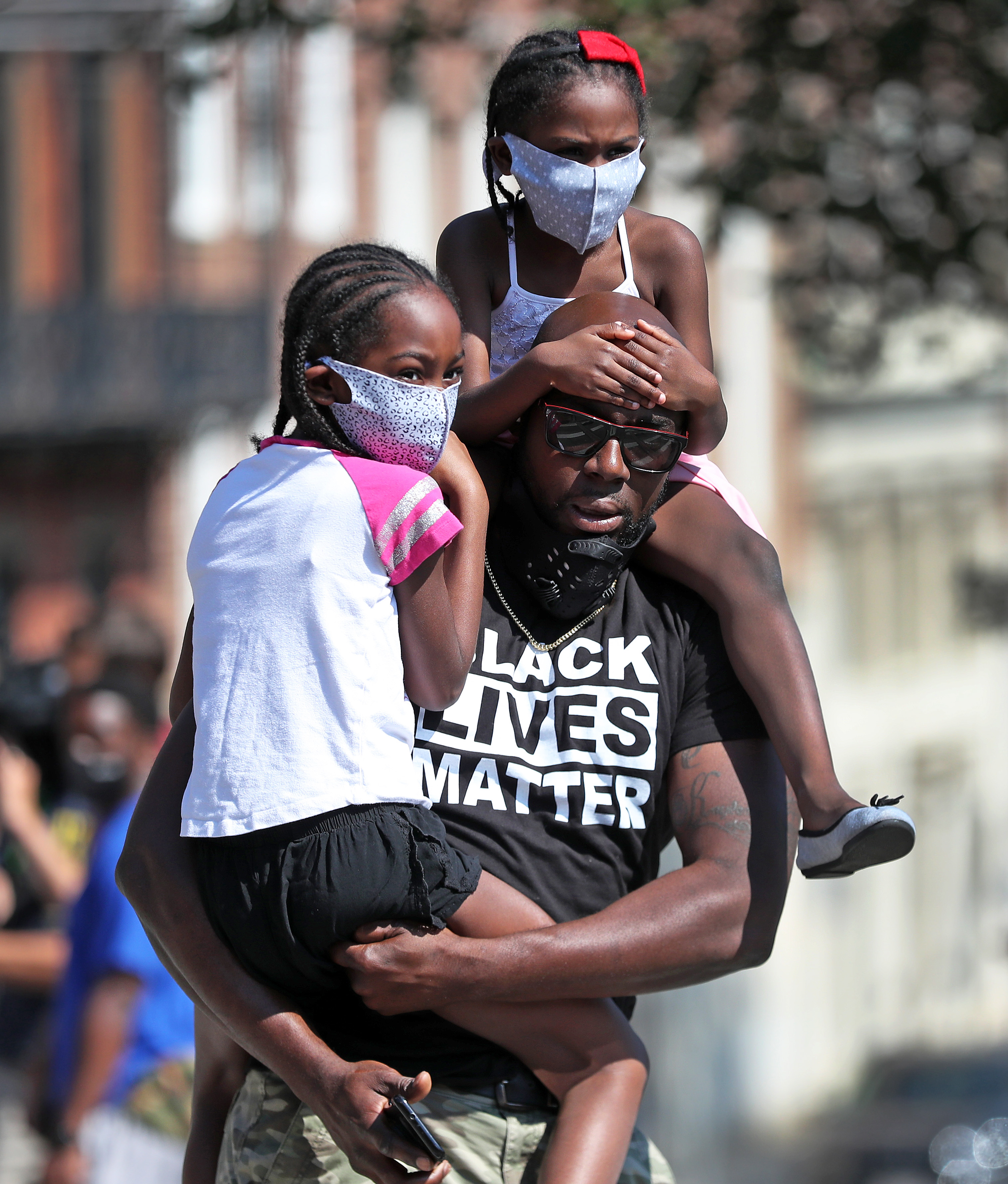 A protest march on June 22 in honor of Rayshard Brooks, sponsored by Black Lives Matter Boston and Violence in Boston Inc., started at the Reggie Lewis Center in Roxbury and ended in front of the State House. A man holds two young children as they listen to a speaker.