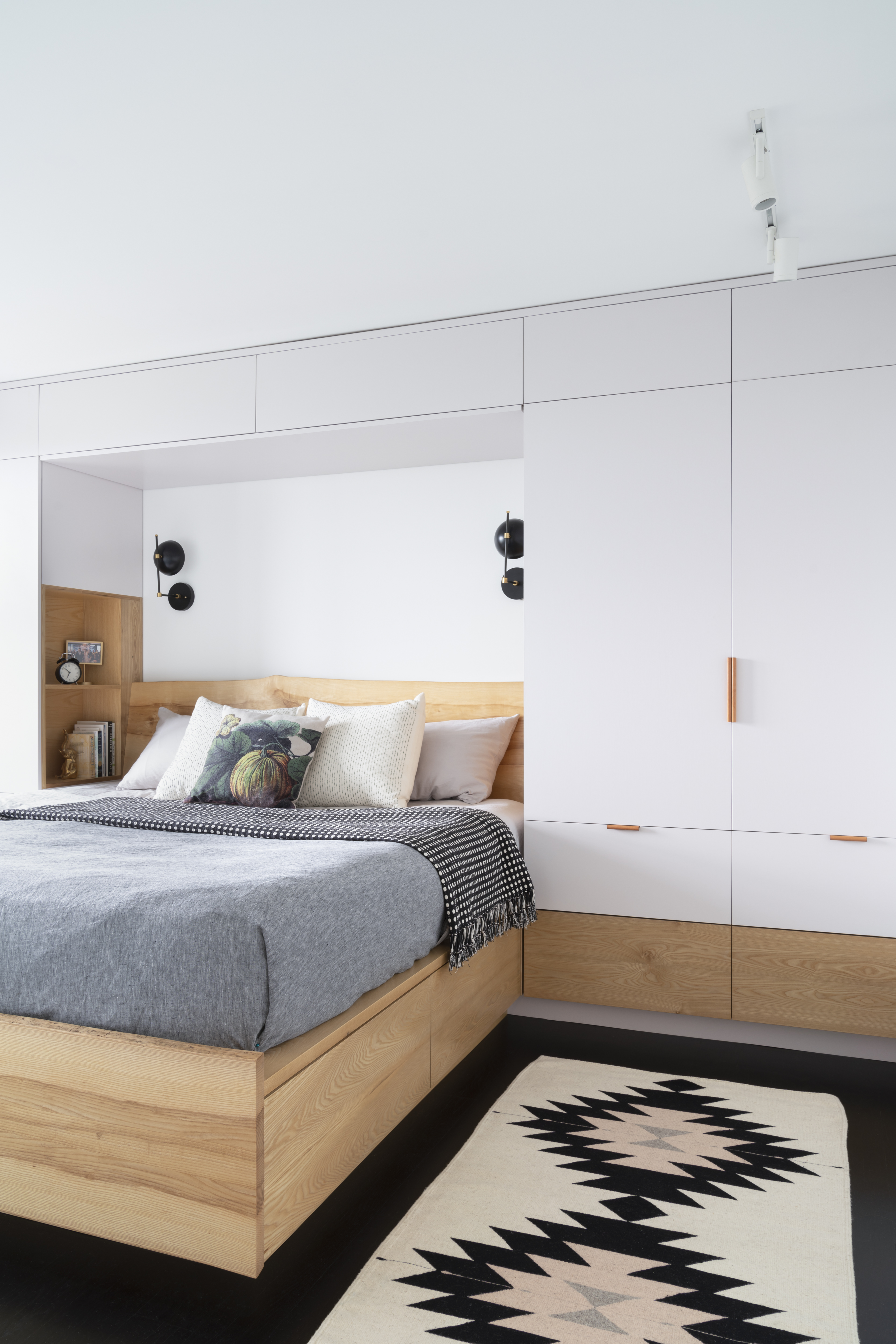 Custom painted birch plywood built-ins surround the oak bed in the primary bedroom.