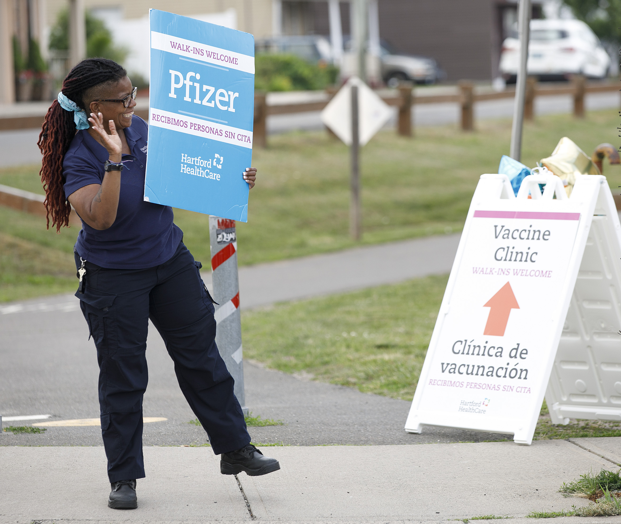 Roslyn Williams, an EMT vaccinator for Hartford HealthCare, holds a Pfizer sign for a COVID-19 vaccination event at Smokin' With Chris in Southington, Conn., Monday, June 21, 2021.