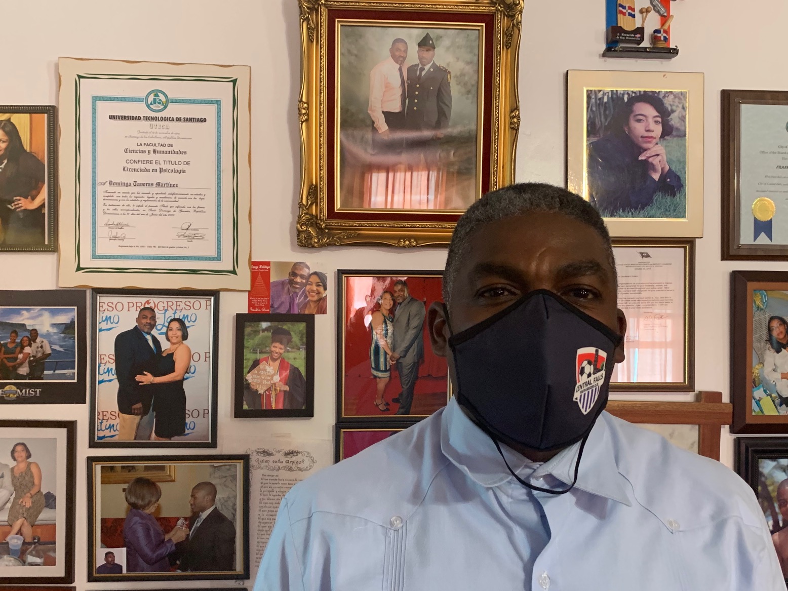 Central Falls City Councilman Franklin A. Solano in front of family photos at his home in Central Falls.