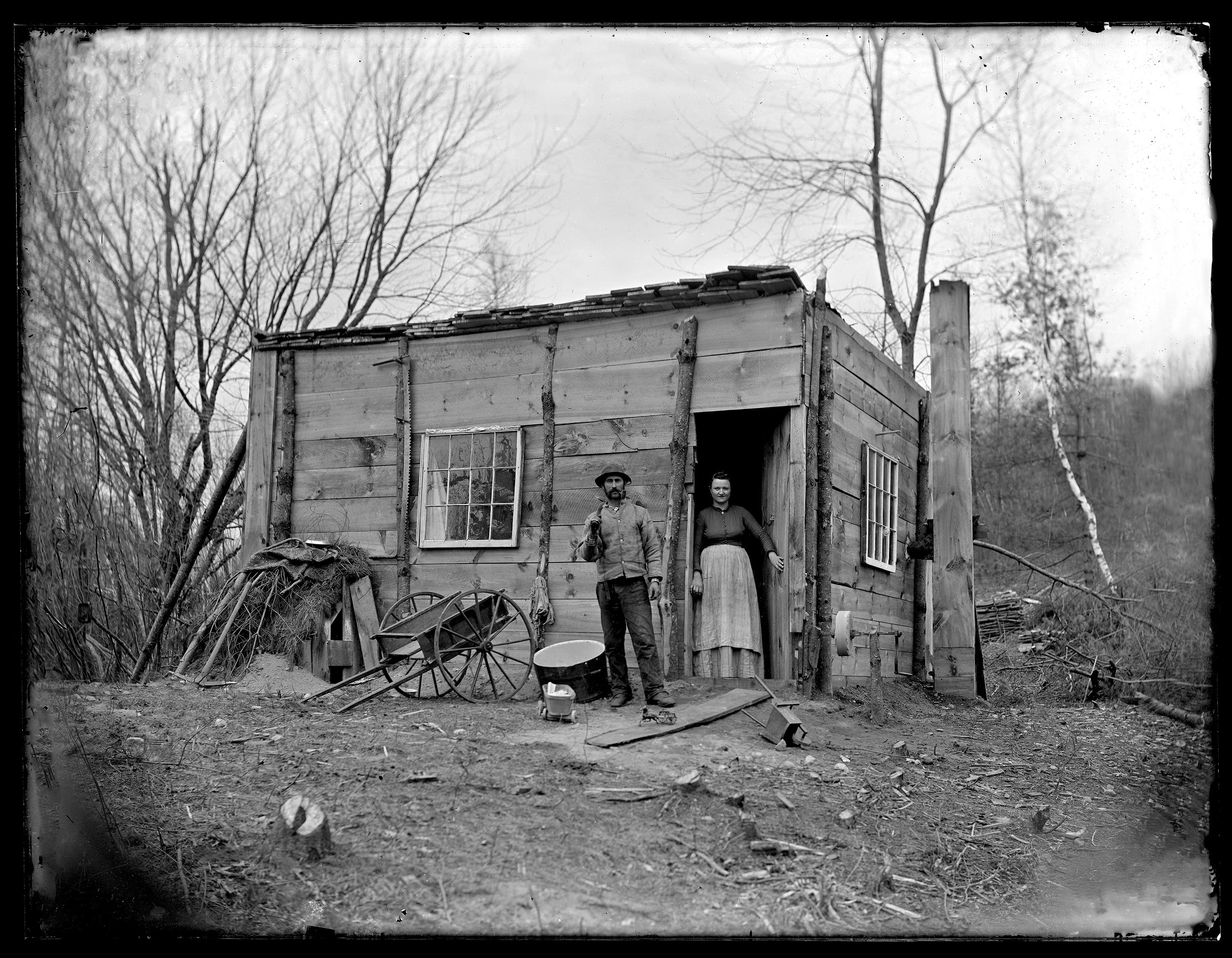 A young couple stood in front of a small cabin in Northfield. Part of the "Somebody Photographed This" collection.