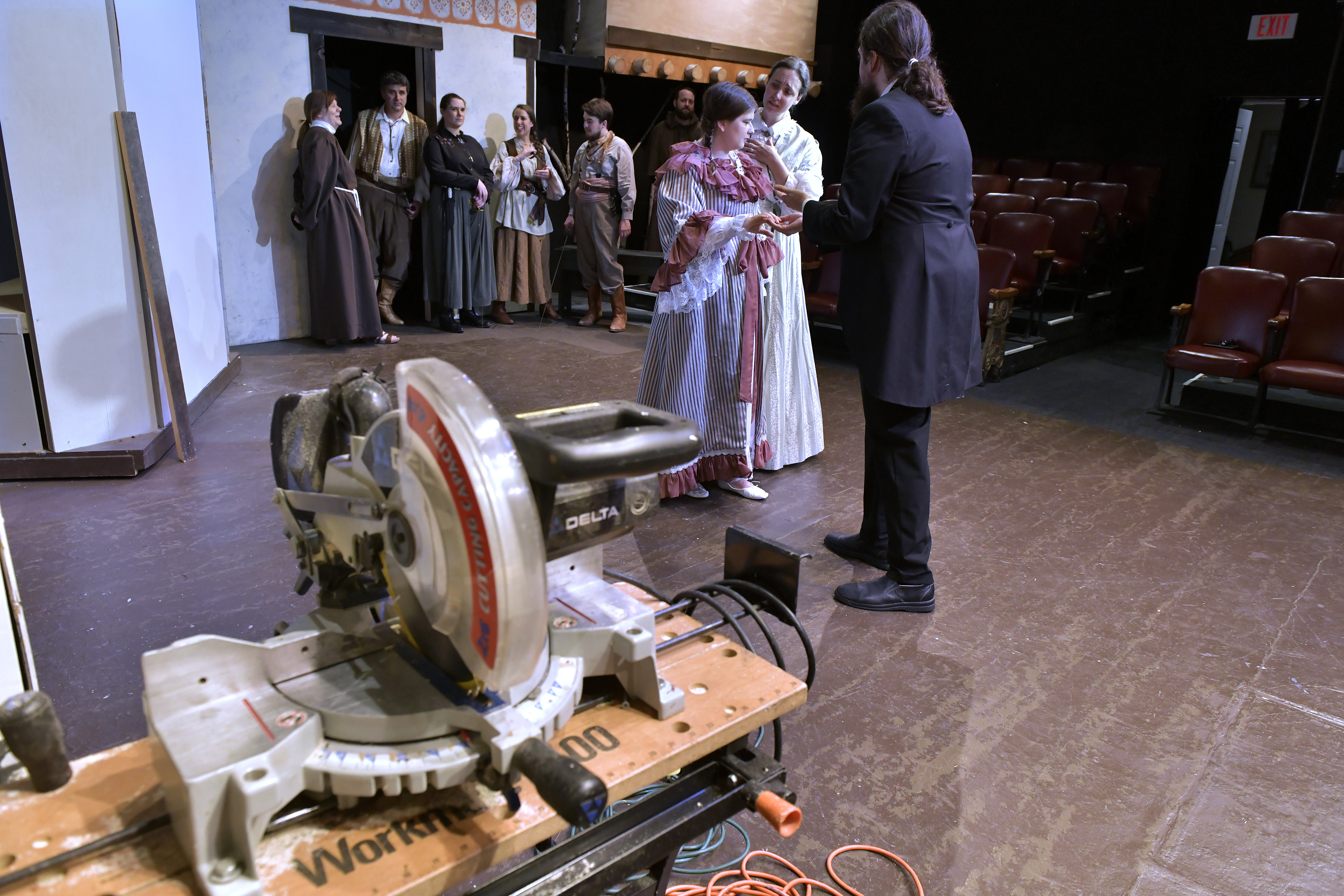On stage, from left, Amanda O'Donnell (Juliet), Sarah Logsdon (Lady Capulet) and Bob Waters (Paris) of The Quannpowitt Players share the stage with a miter saw as they rehearse their upcoming production of "Romeo and Juliet."