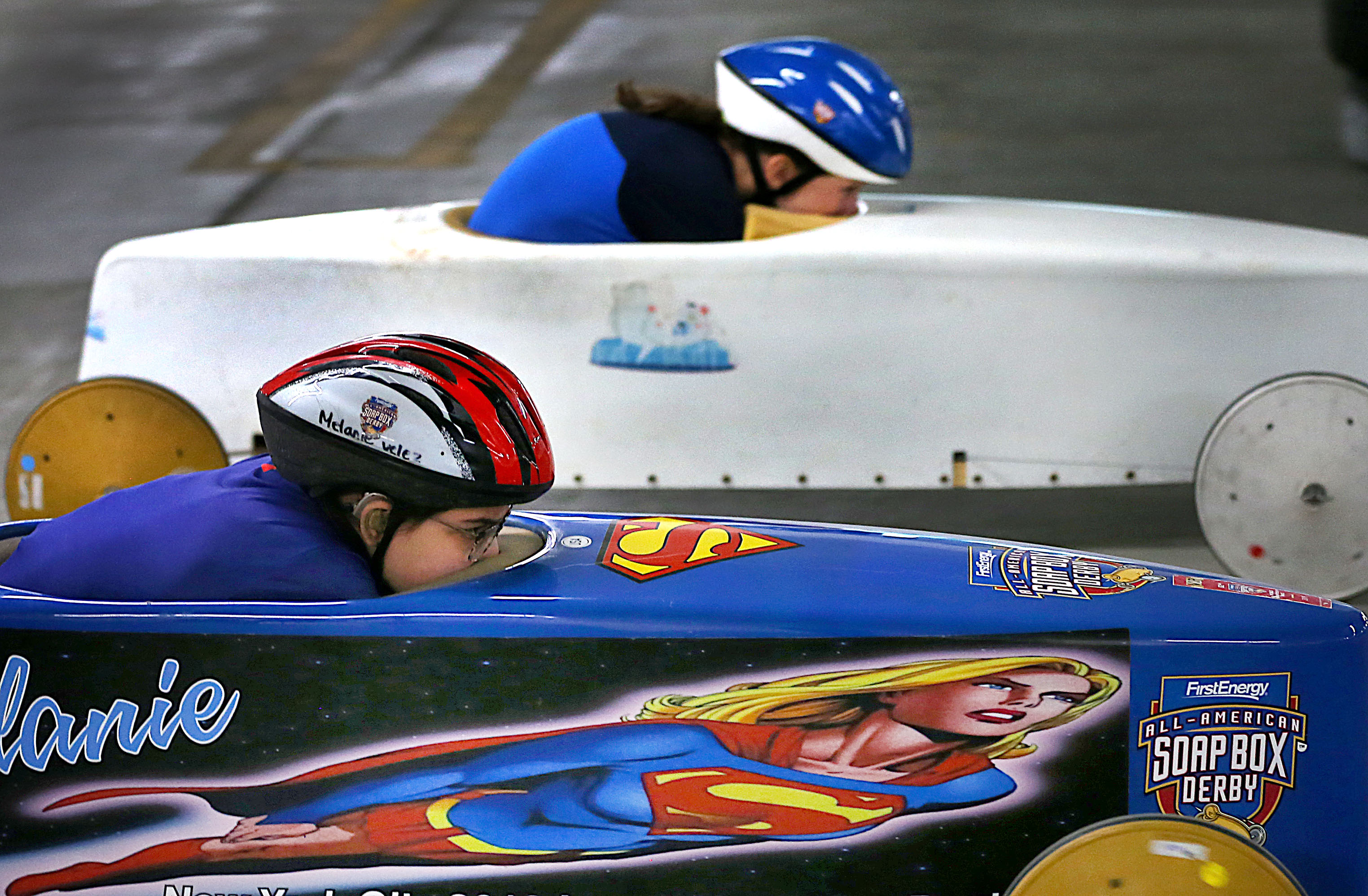 For the third year in a row, the Arlington/Cambridge Soap Box Derby Winter Rallies were held inside the parking garage of the Cambridgeside shopping mall on March 7 These two racers were nose to nose halfway down the track.