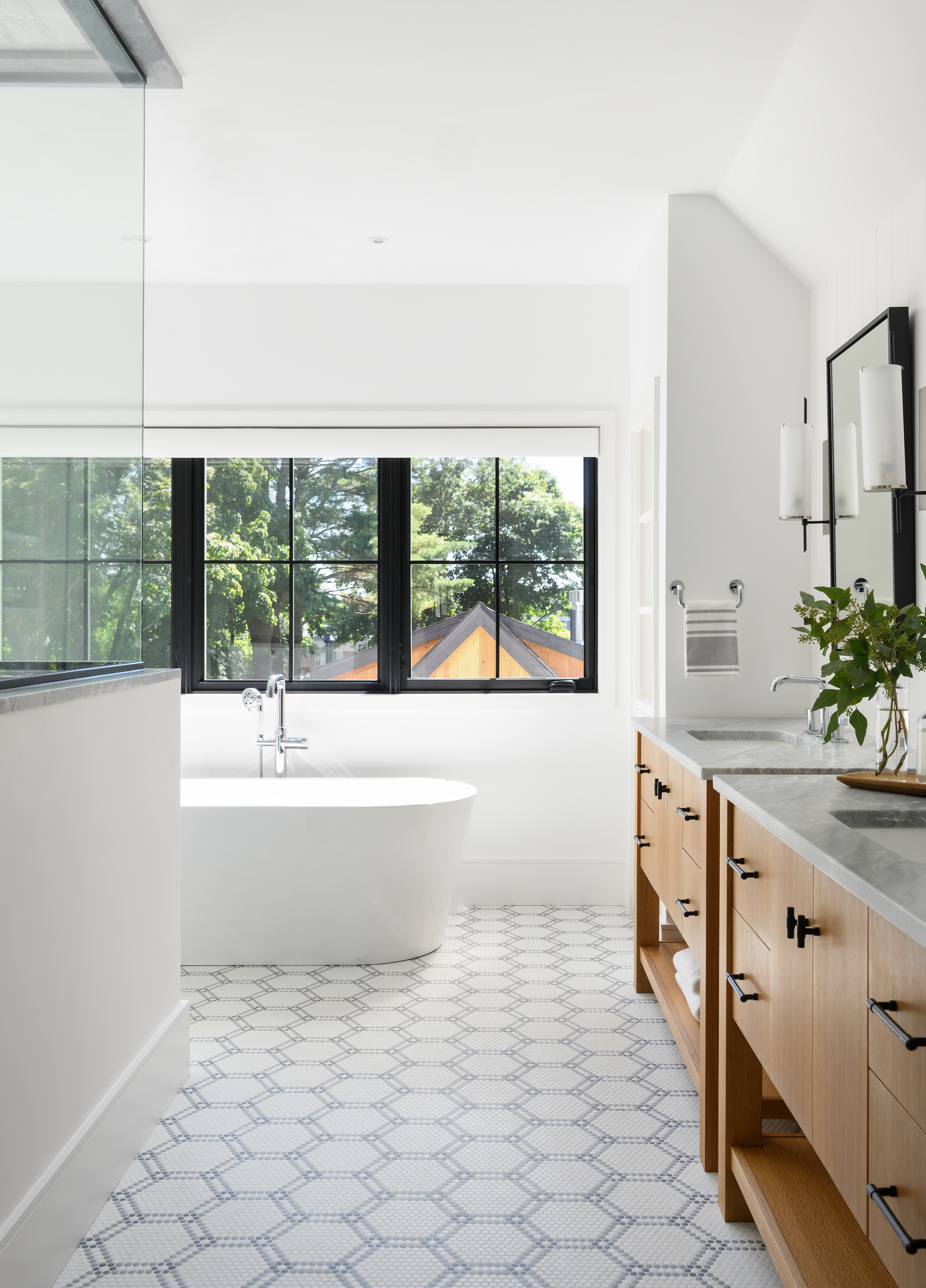 Vertical shiplap adds interest behind the vanities, also by Red Birch Designs, while the pattern of the mosaic tile helps break up the large expanse of floor.