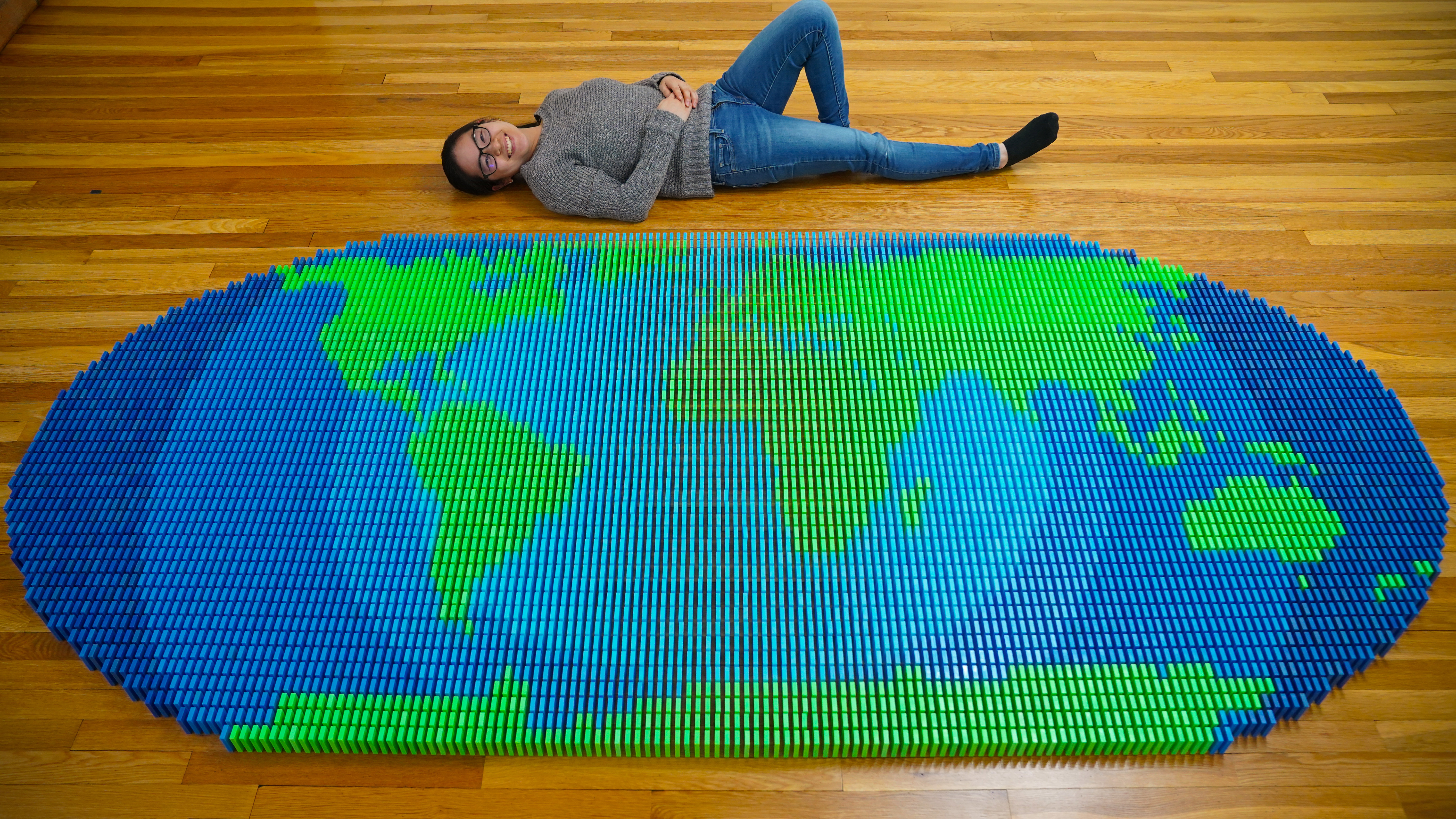 Lily Hevesh with a map of the world made of dominoes that she created. From "Lily Topples the World."