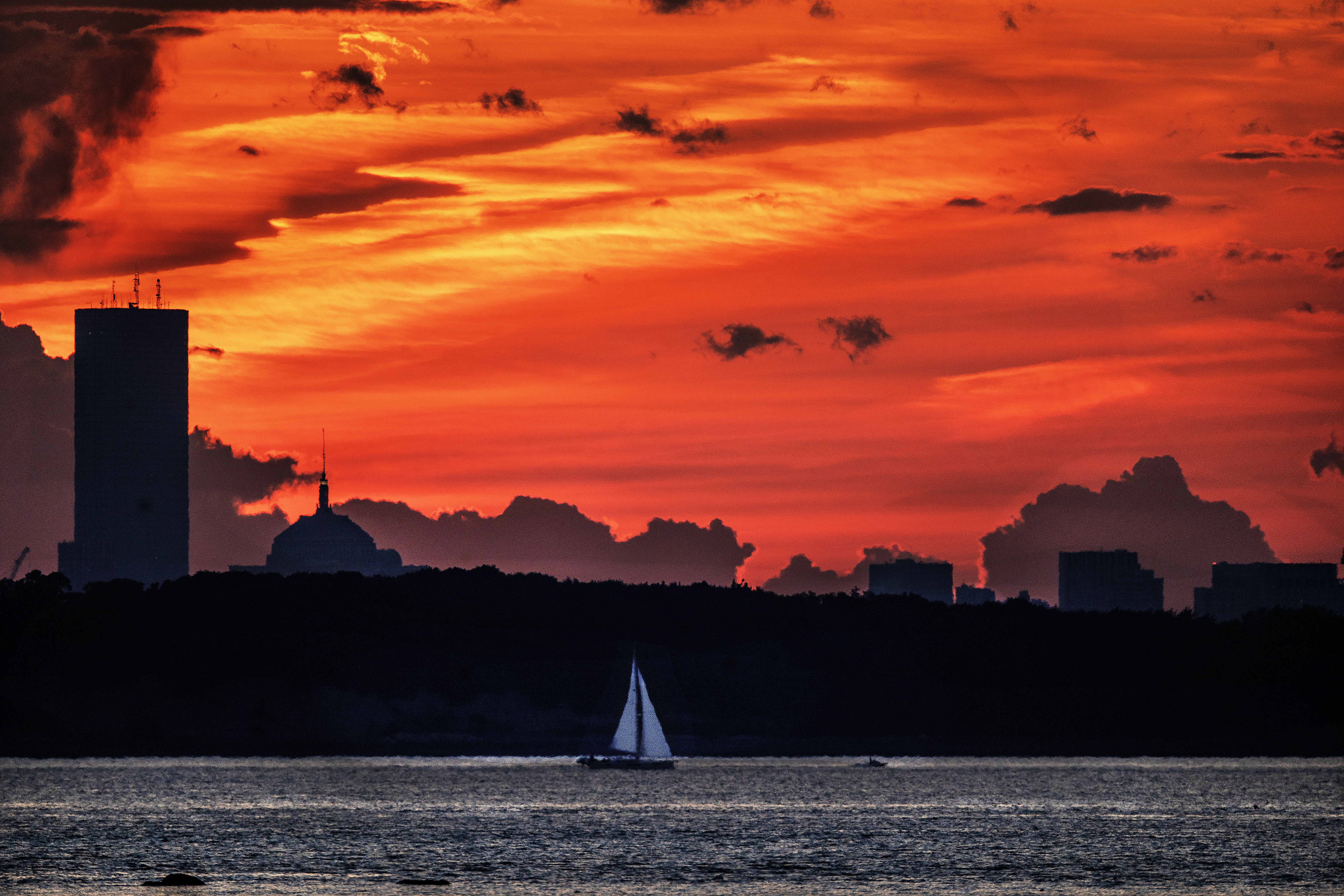 A sailboat glided past the Boston skyline just after sunset.