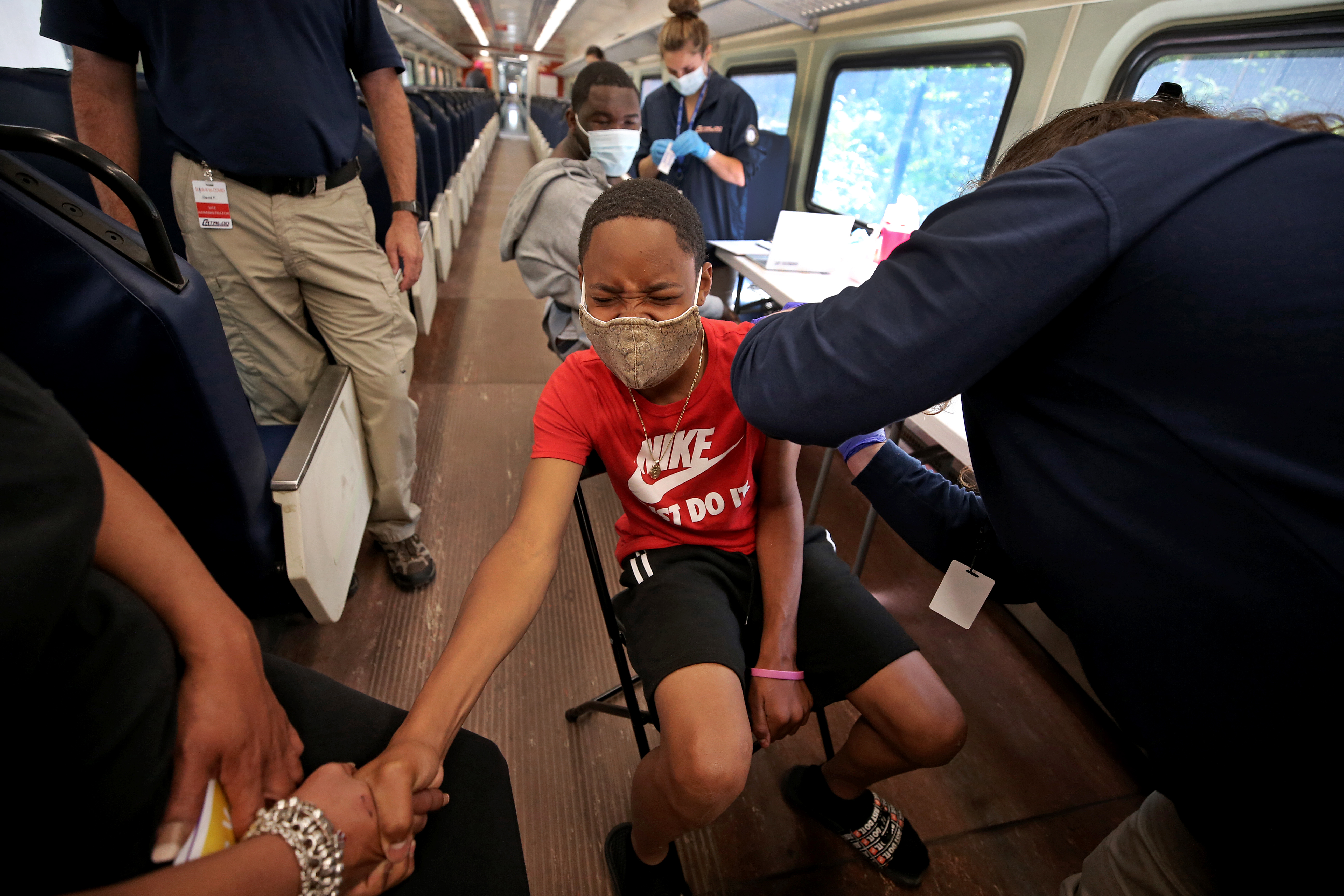 Omari Long, 12, held his mother's hand as he got a COVID-19 shot while on the Vax Express.