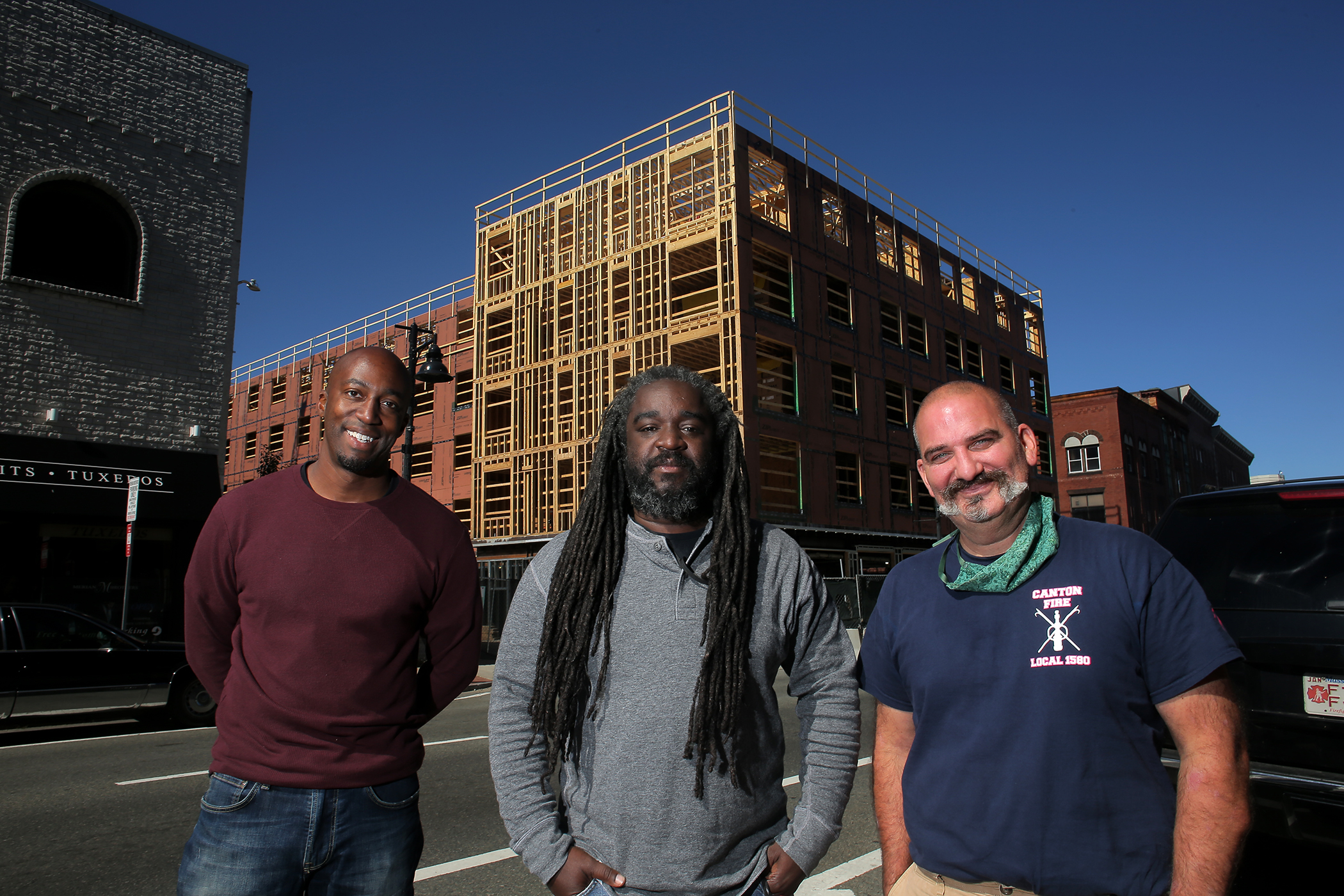 Founders of the Brockton Brewing Company Eval Silvera, Pierre Alexandre, and Rowan Olmstead pose in front of the new building on Main Street where their brewery will be housed in Brockton.
