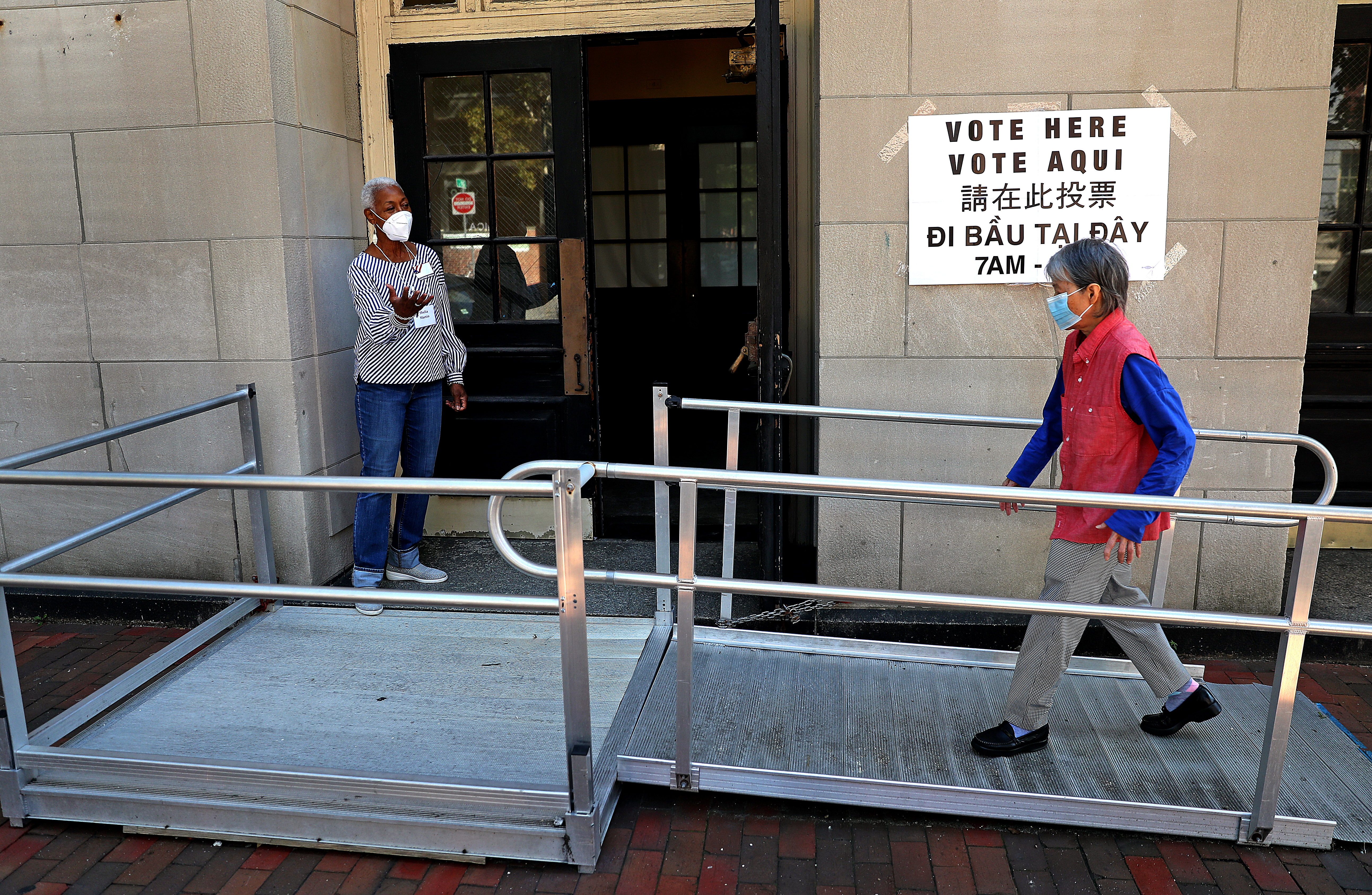 Shelia Martin, an election official at Ward 5 Precinct 1 helps with directing a voter to the polling place held at the Benjamin Franklin Institute of Technology in Boston.